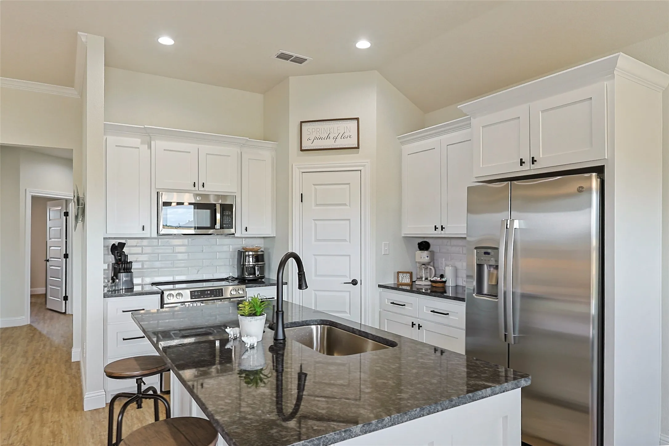Kitchen featuring a central island with an undermount sink, granite countertop, and black faucet
