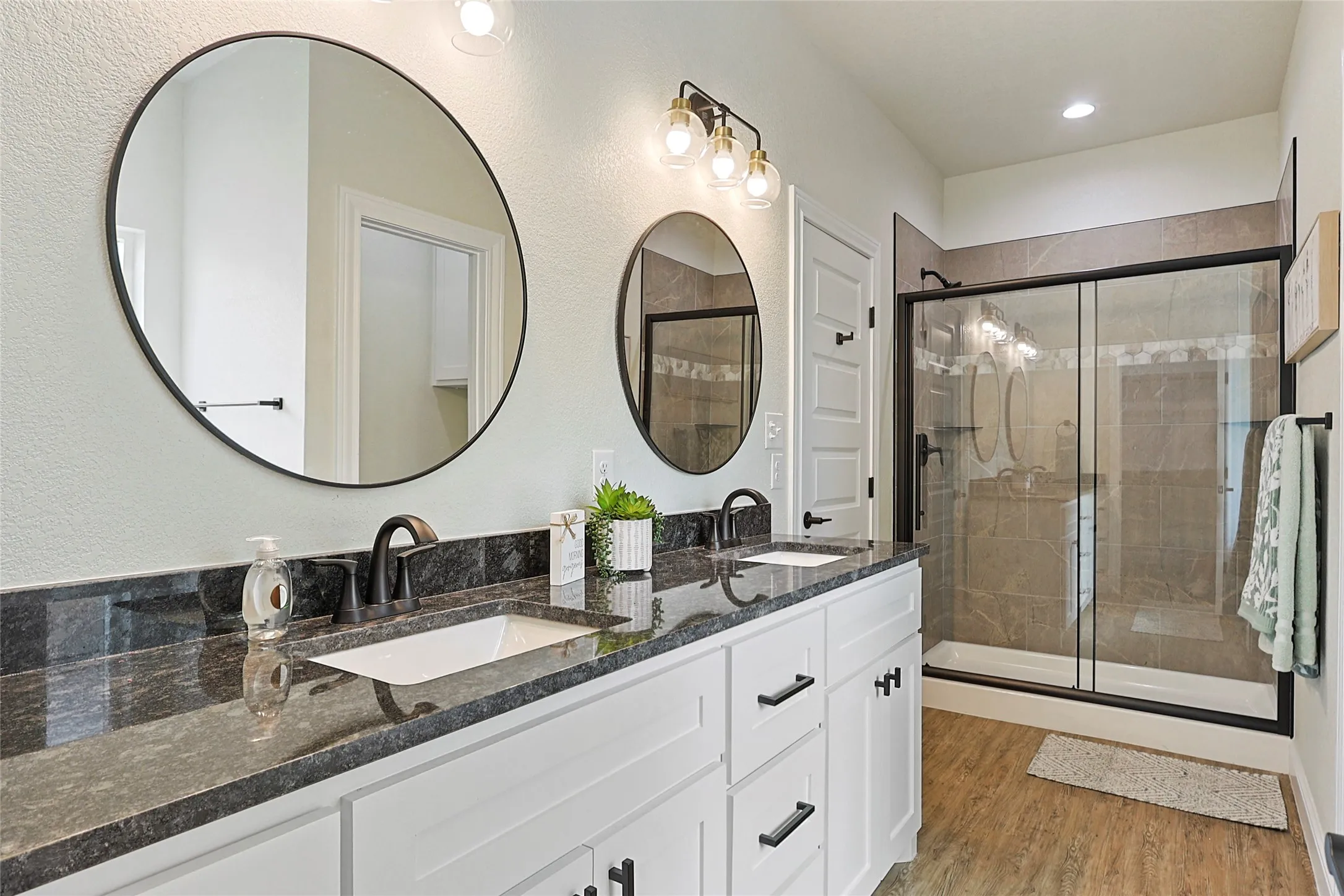 Dual vanity with dark stone-finish countertop and white cabinetry