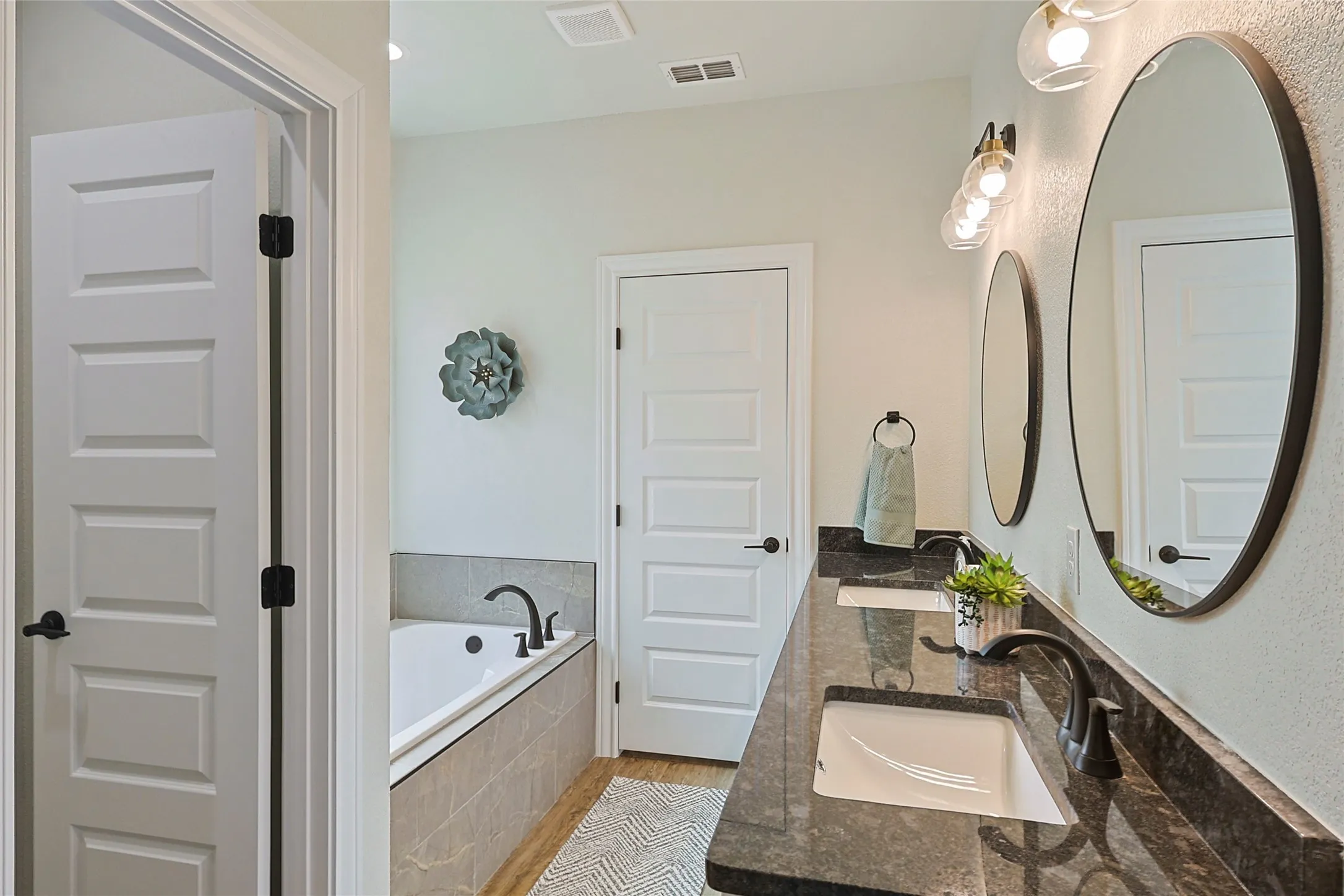 Double vanity with dark countertops and modern black hardware