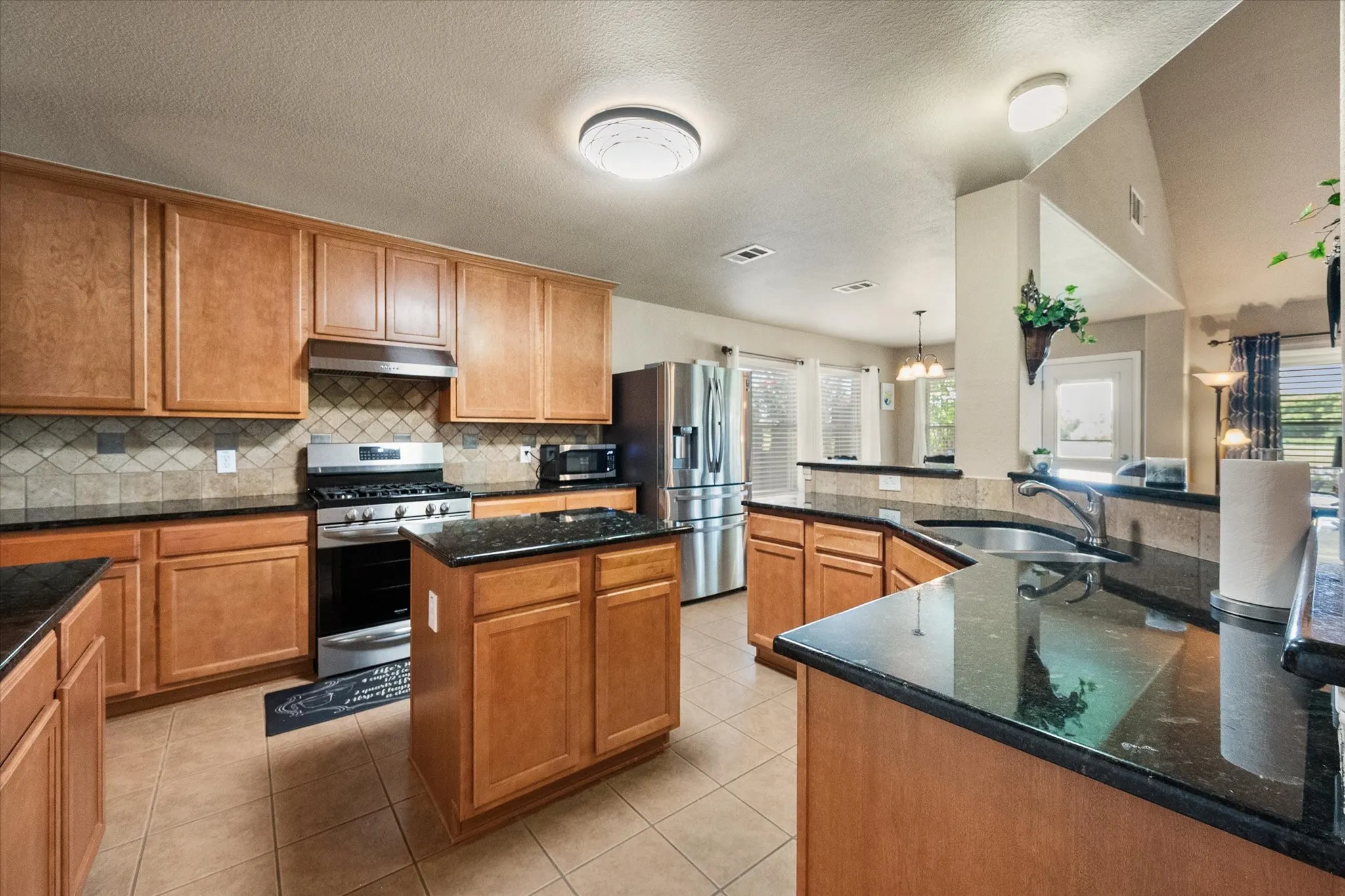 The heart of this **Mira Lagos home** is the spacious **open-concept kitchen**, thoughtfully designed for everyday living and effortless entertaining. Featuring a large **center island**, **granite countertops**, abundant **custom wood cabinetry**, and a stylish **tile backsplash**, this kitchen offers both beauty and functionality. The **gas range**, stainless steel appliances, and expansive counter space make meal preparation a breeze, while the breakfast bar provides additional seating for family and guests. Overlooking the living room and breakfast area, the open layout keeps everyone connected. A **large walk-in pantry**, double-basin sink, and abundant storage complete this chef-inspired kitchen, making it a standout feature for buyers seeking a **move-in ready home in Mira Lagos, Grand Prairie, TX**.