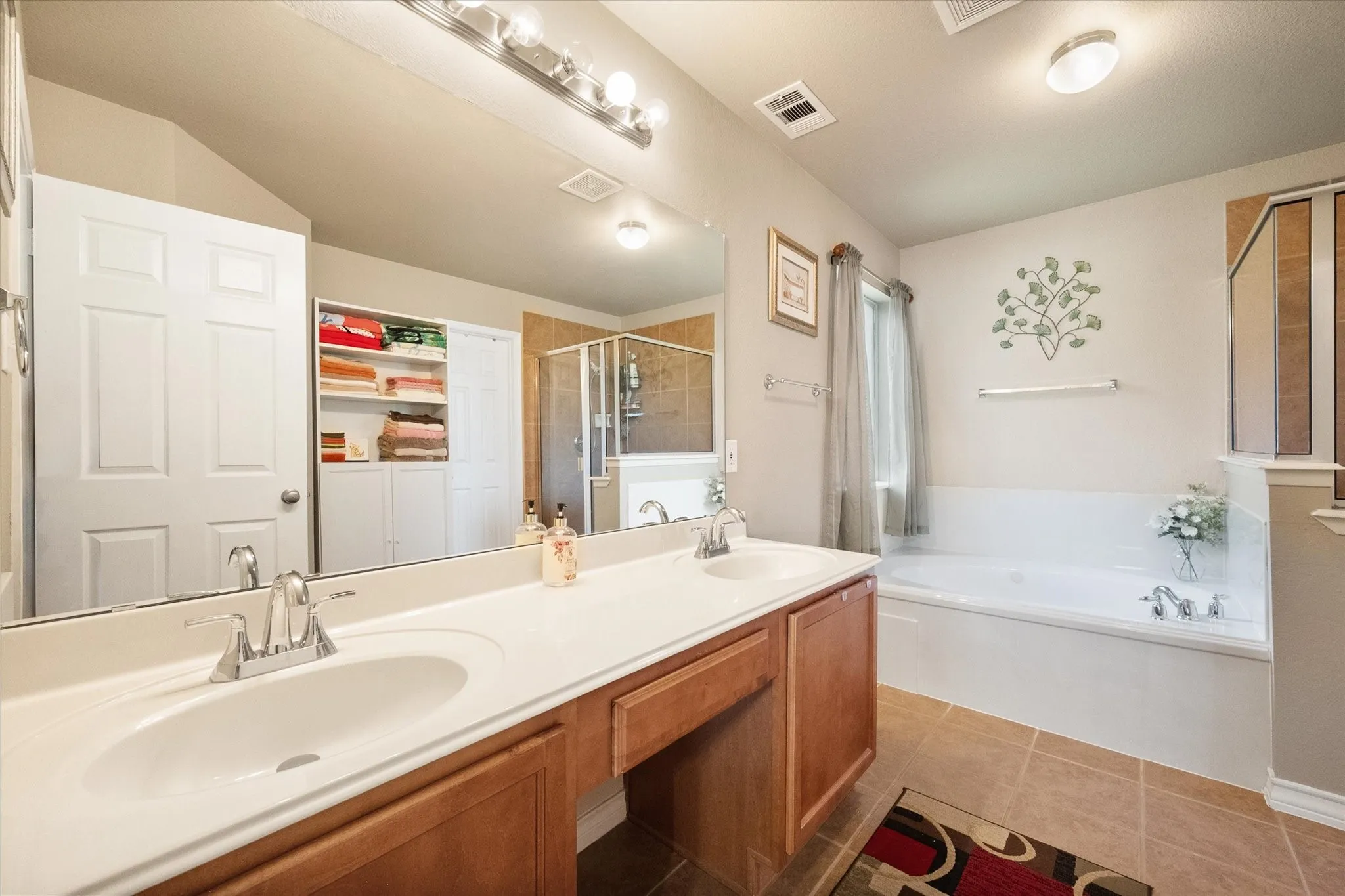 Unwind in this spacious primary bathroom, thoughtfully designed with a dual-sink vanity, expansive mirror, and abundant counter space for everyday convenience. The spa-inspired layout features a relaxing soaking tub and a separate glass-enclosed shower, offering the perfect combination of luxury and functionality. Warm tile flooring, natural light, and generous storage complete this well-appointed ensuite, creating a private retreat ideal for starting and ending your day in comfort.