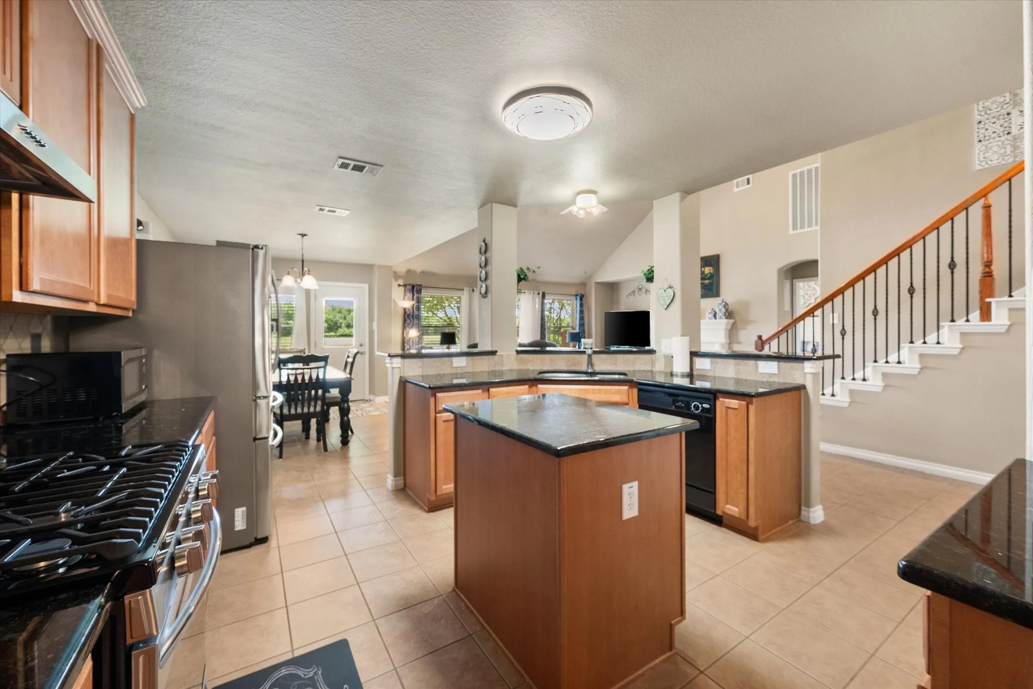 This **open-concept gourmet kitchen** is designed for both everyday living and effortless entertaining. Featuring a large **center island**, beautiful **granite countertops**, abundant **custom wood cabinetry**, and a stylish **tile backsplash**, this kitchen offers exceptional workspace and storage. The **gas range**, stainless steel appliances, breakfast bar, and expansive prep areas make cooking a pleasure. The kitchen flows seamlessly into the spacious family room and breakfast nook, allowing you to stay connected while entertaining. Soaring ceilings and the open sightlines create a light, airy feel, while the oversized island serves as the heart of the home. Perfect for buyers searching for a **move-in ready home with an open floor plan, gourmet kitchen, granite counters, gas cooking, and abundant cabinet space in Mira Lagos, Grand Prairie, TX**.
