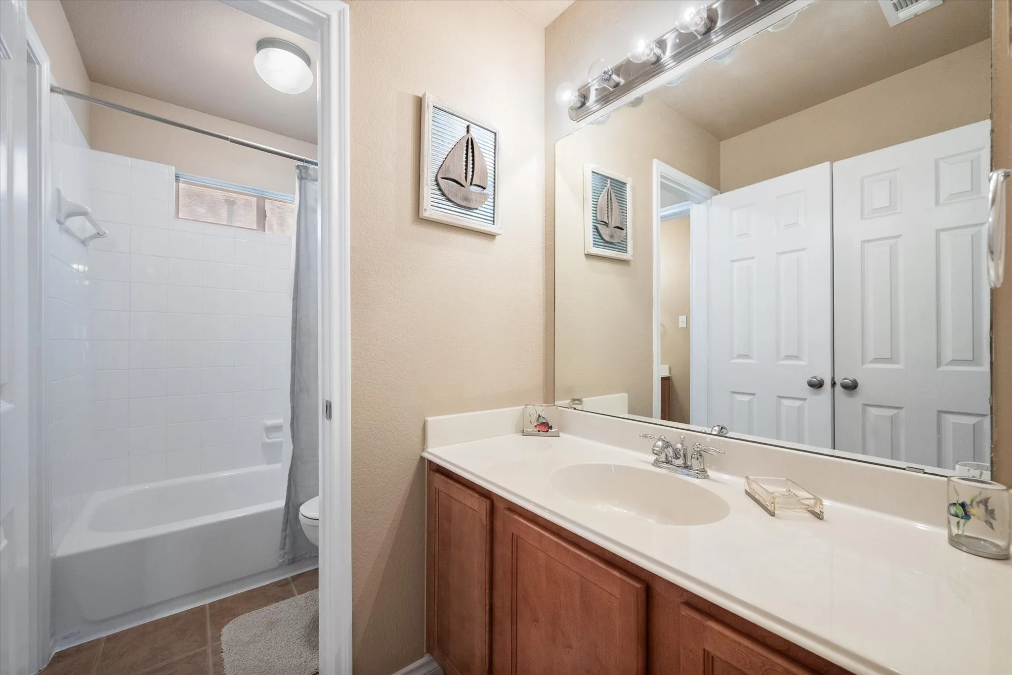 This well-appointed upstairs secondary bathroom offers both style and functionality with a single-sink vanity, extended countertop, and a full tub/shower combination. Bright lighting, a large framed mirror, and neutral finishes create a clean, inviting space that's ideal for family members or guests. A privacy window brings in natural light while maintaining seclusion, and the spacious vanity provides ample storage and prep space for everyday convenience. Perfectly positioned to serve the upstairs secondary bedrooms, this move-in-ready bathroom combines comfort, practicality, and timeless appeal.