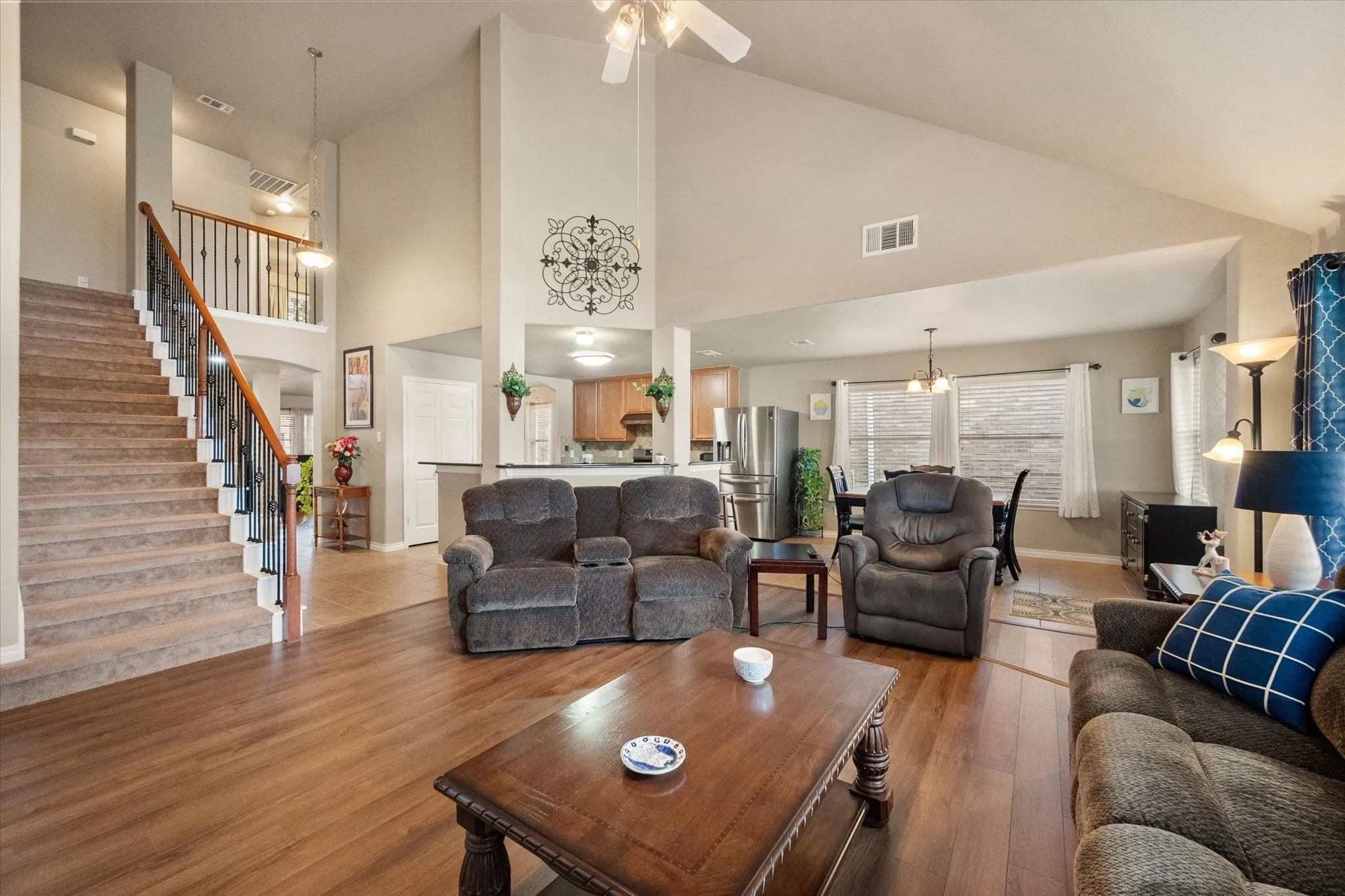 Experience the beauty of this spacious open-concept living room, highlighted by soaring vaulted ceilings, elegant architectural details, and rich luxury vinyl plank flooring. Designed for modern living, the expansive floor plan seamlessly connects the living room, kitchen, breakfast area, and staircase, creating an ideal space for entertaining and everyday comfort. Warm neutral tones, abundant natural light, and a ceiling fan enhance the inviting atmosphere, while the open sightlines emphasize the home's impressive scale and functionality. This bright, airy gathering space offers the perfect combination of style, comfort, and versatility