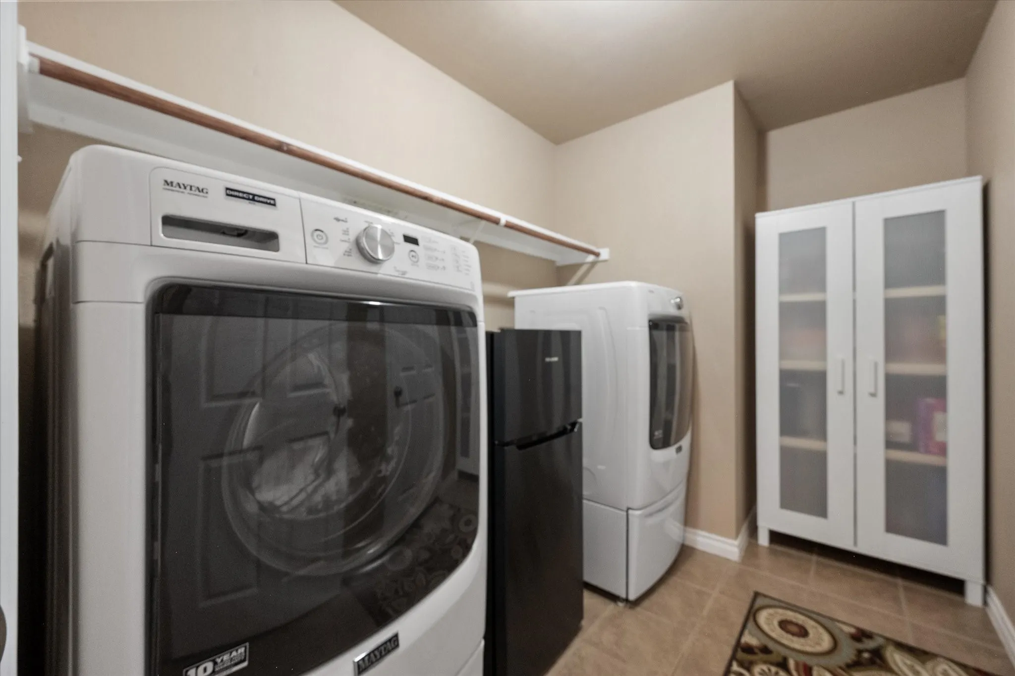 Spacious laundry room with abundant storage and functionality, large enough for a modern front-load washer and dryer, built-in shelving, and plenty of space for folding, organizing, and everyday household tasks. This well-designed utility room offers room for additional cabinetry, a second refrigerator or freezer, and extra storage to keep your home organized. Conveniently located and thoughtfully sized, this oversized laundry room combines efficiency with practicality for today's busy lifestyle.