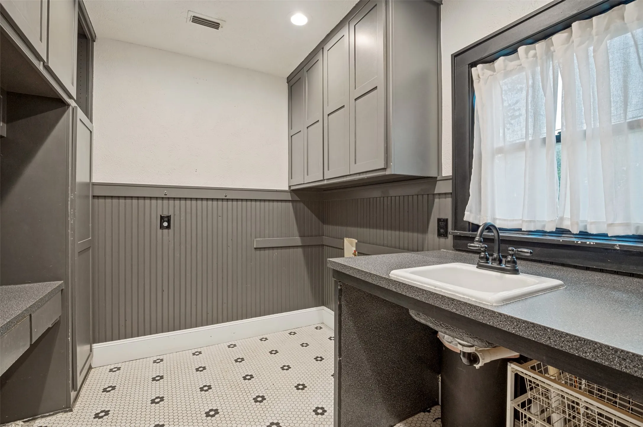 Large Laundry Room with storage, built in desk and sink.