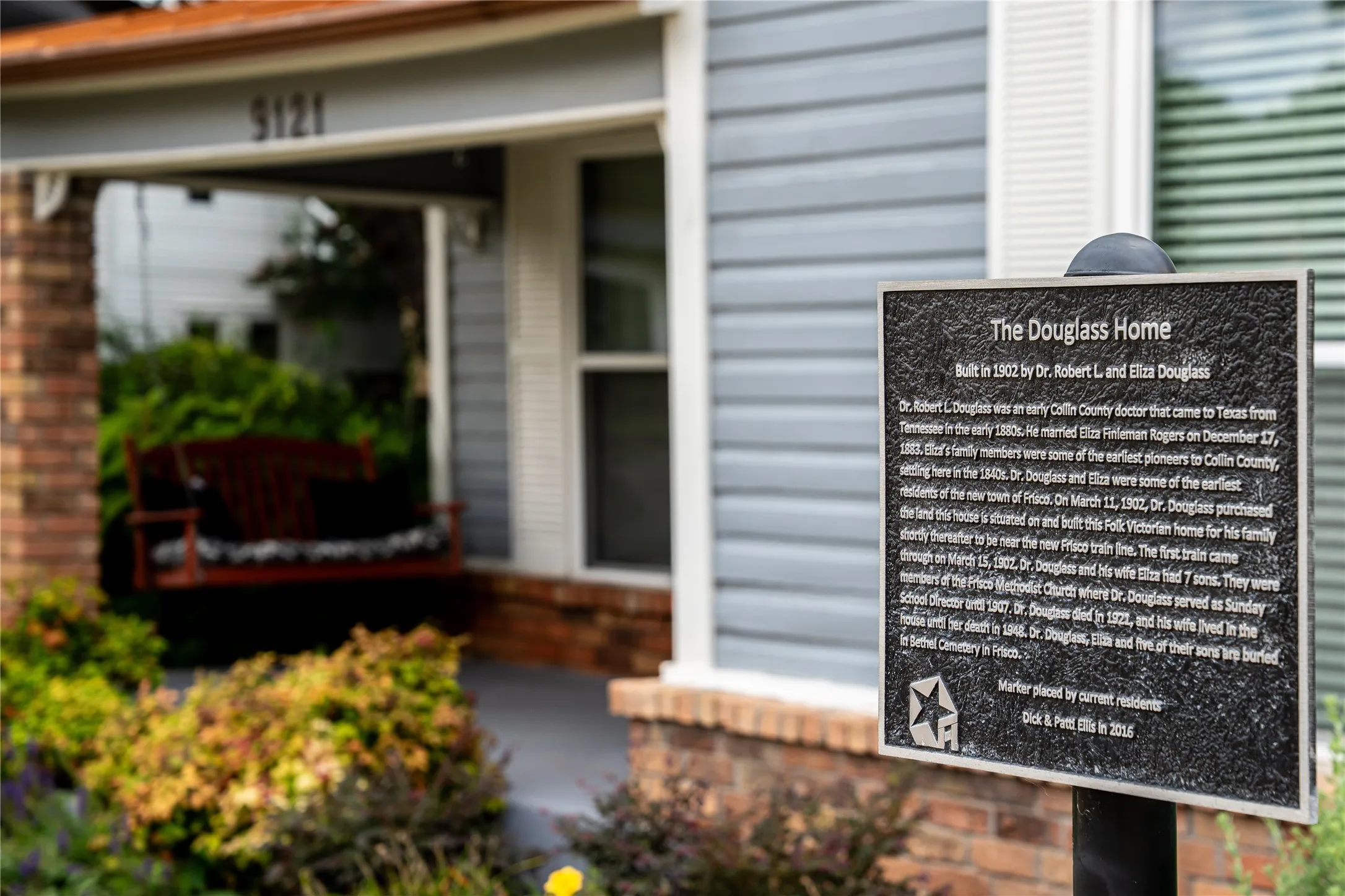 Charming front porch with The Douglas home placard in front yard.