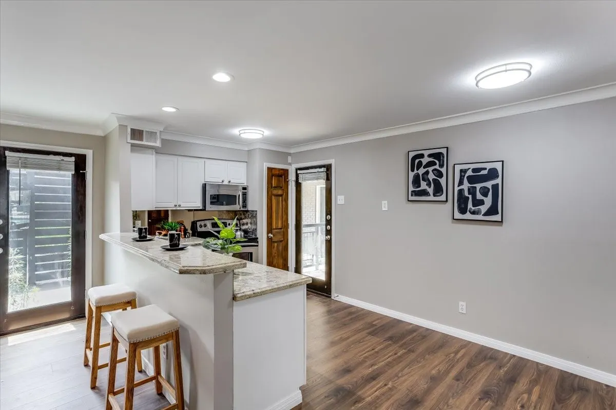 Kitchen featuring a breakfast bar with stone-finish countertop, white cabinetry, and stainless steel appliances