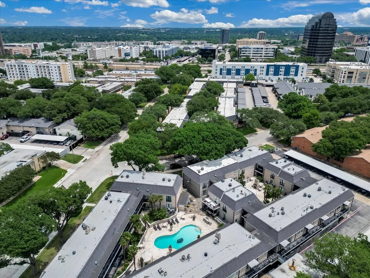 Multi-unit residential property featuring a central courtyard, an outdoor swimming pool with surrounding lounge space, and multiple covered parking structures