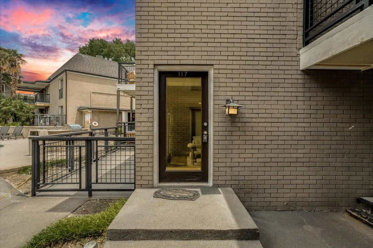 Exterior featuring a brown brick facade and a dark-framed entry door with transom window
