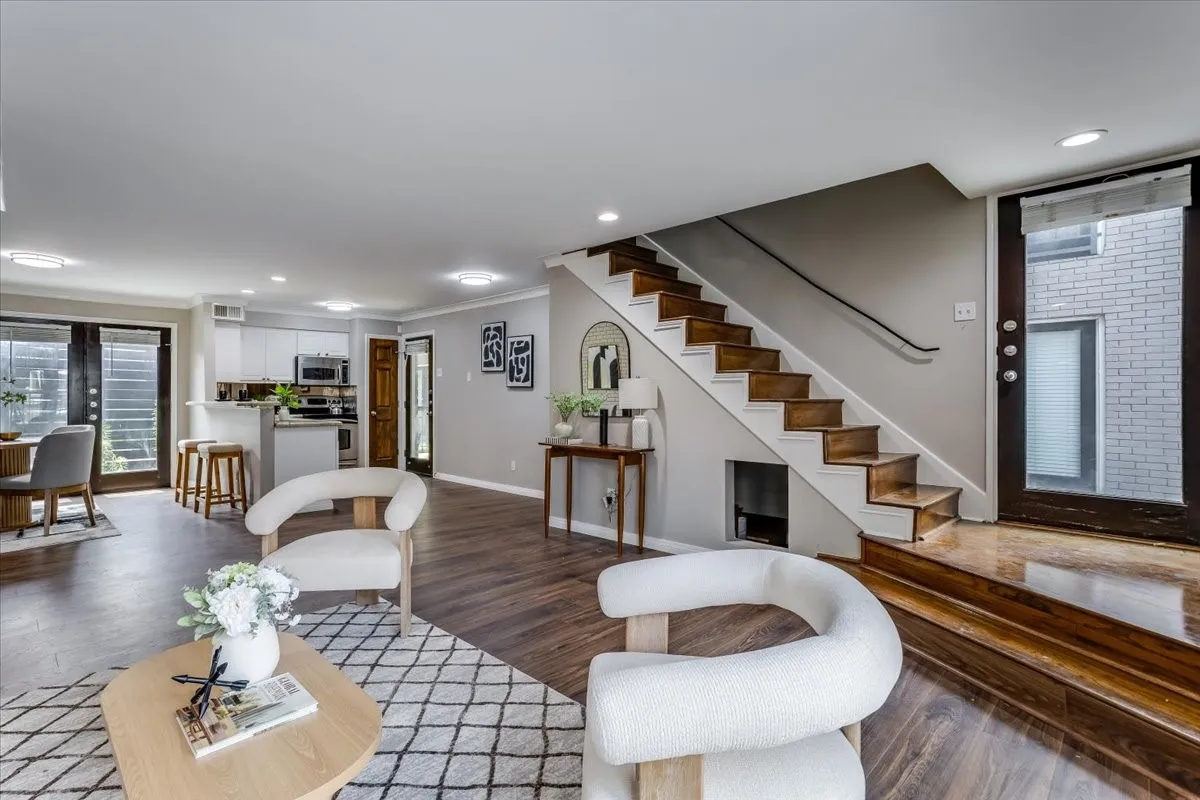 Open-concept living area featuring wood-finish flooring, a contemporary staircase with a dark wood handrail, and recessed lighting
