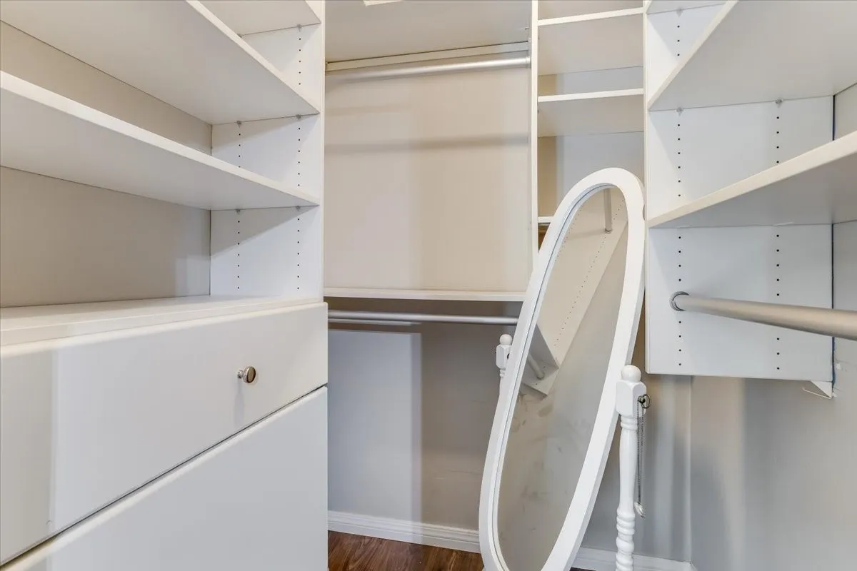 Custom closet system featuring white shelving, integrated drawers with brushed nickel hardware, and multiple hanging rods