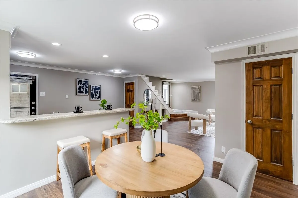 Open-concept living area featuring wood-finish flooring, a breakfast bar with stone countertop, and recessed lighting