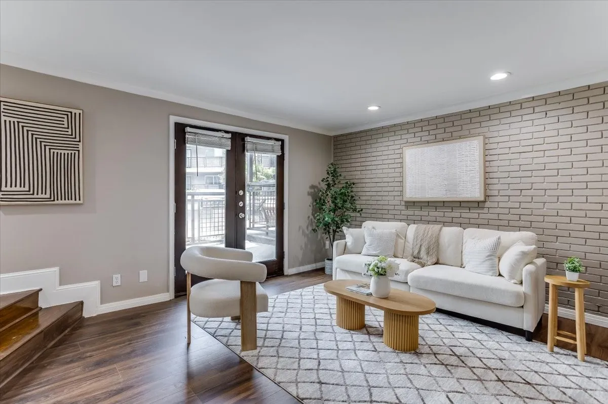Living space featuring a brick accent wall, recessed lighting, and wood-finish flooring