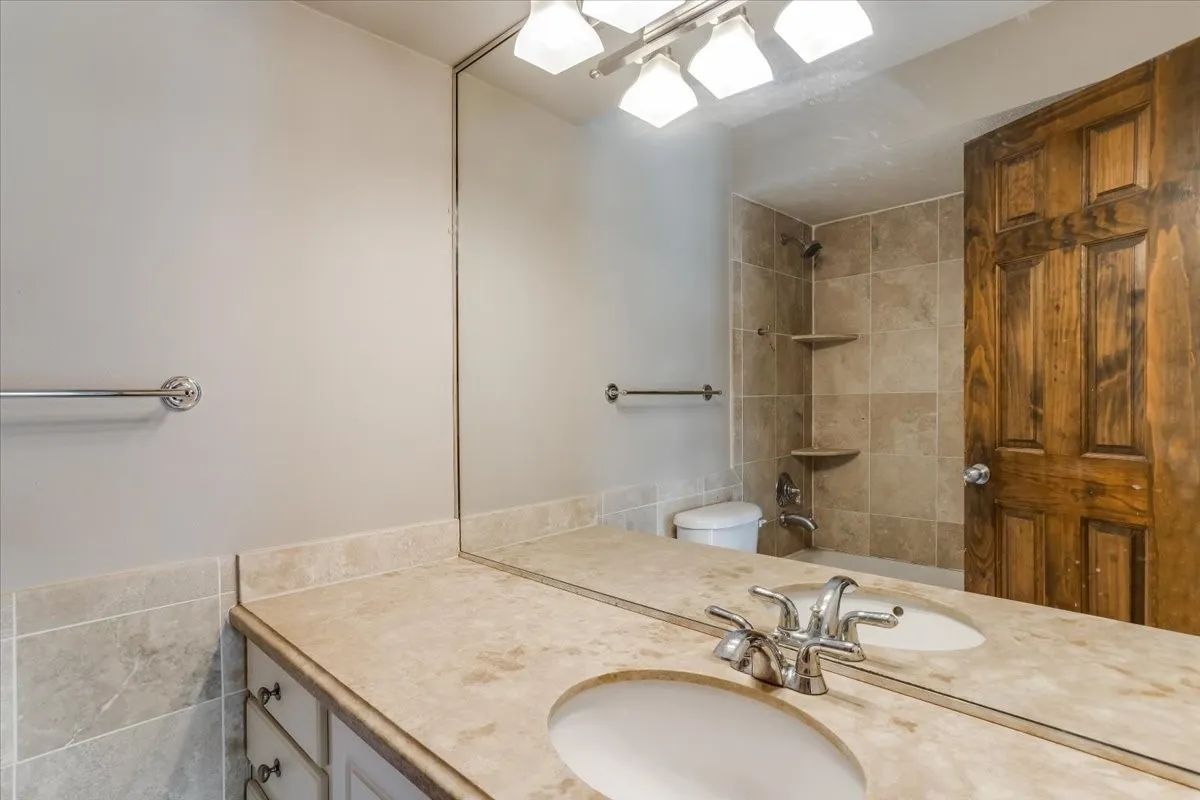 Bathroom featuring a dual sink vanity with a stone-look countertop and chrome fixtures
