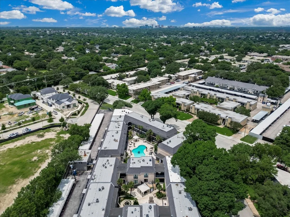 Aerial view of a residential complex featuring multiple buildings with light-colored exteriors and dark roofing
