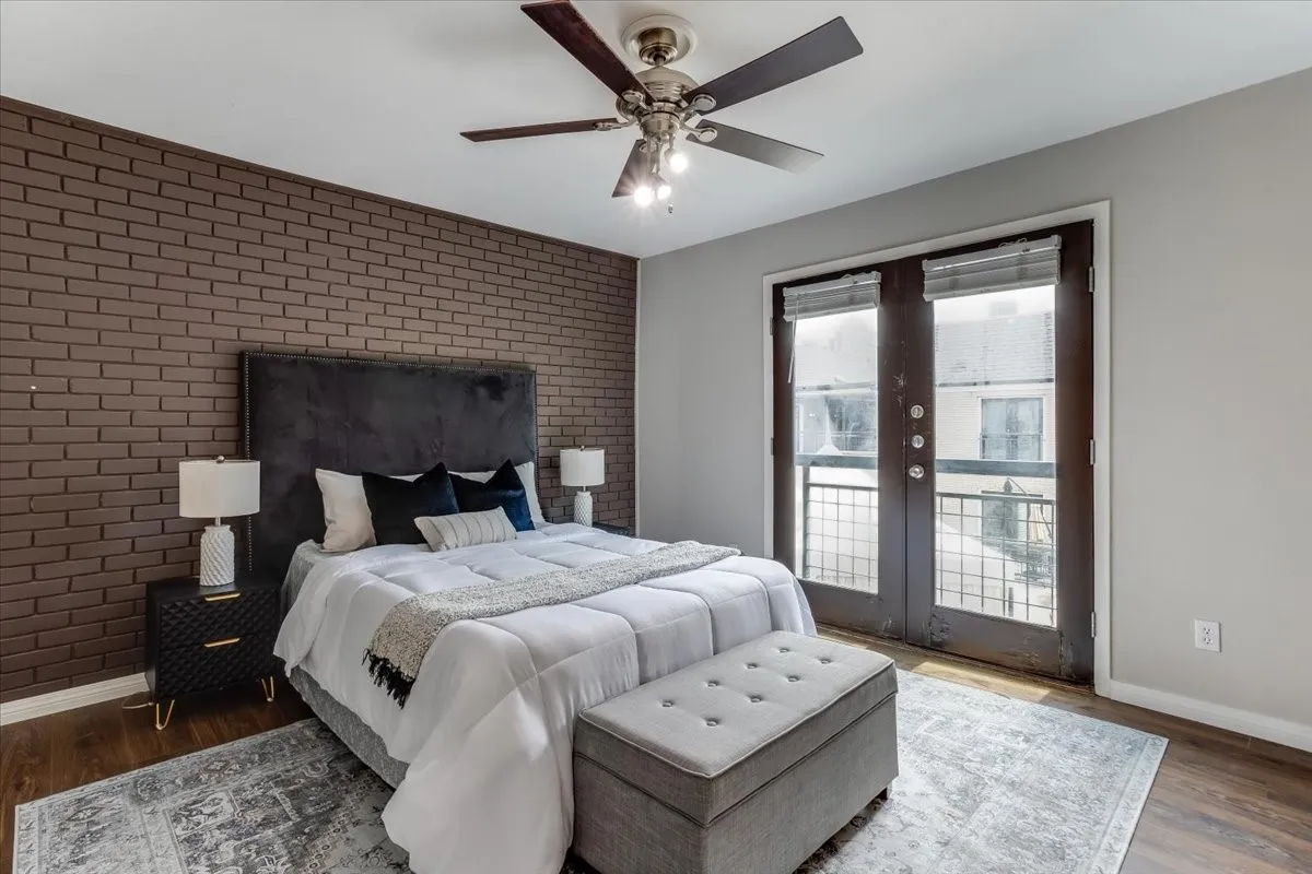 Bedroom featuring an accent brick wall and wood-finish flooring