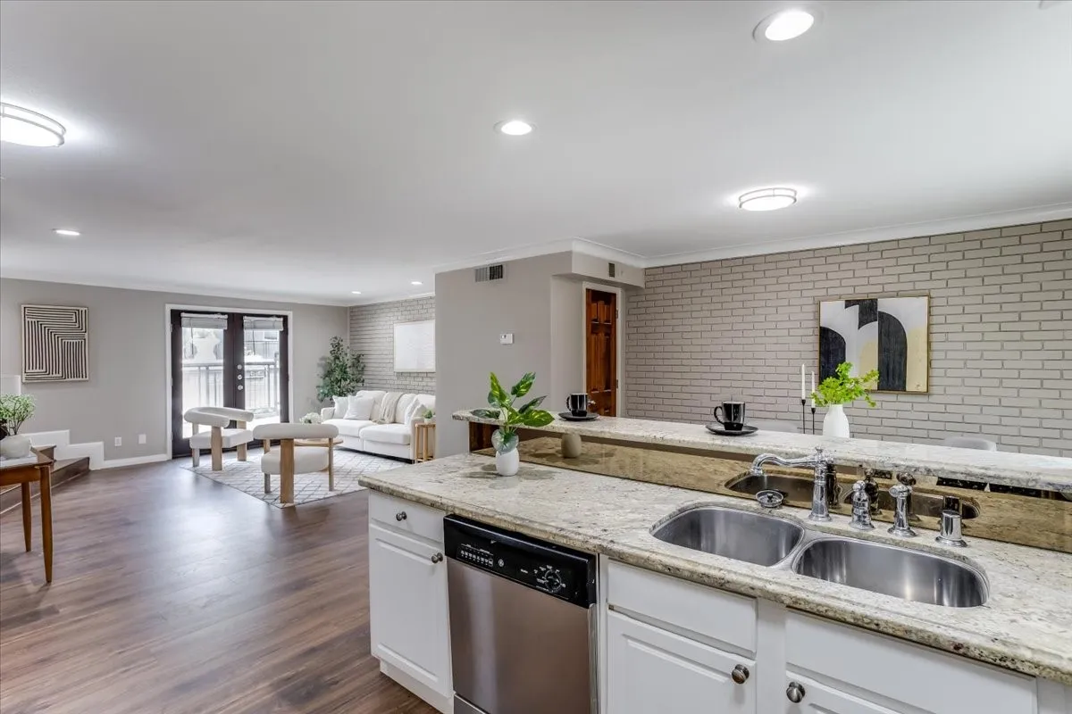Kitchen featuring a double basin sink, granite-style countertops, white cabinetry, and a stainless steel dishwasher
