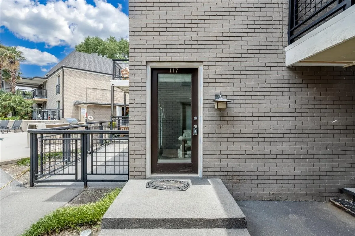 Entry with a dark-framed glass door, exterior wall lantern, and concrete steps