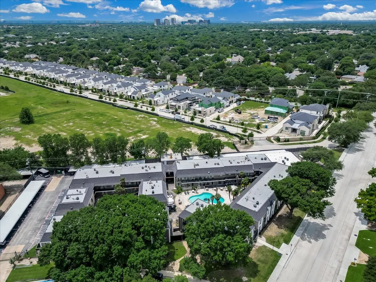 Multi-building property featuring a central courtyard with a swimming pool, extensive paved parking areas, and mature trees