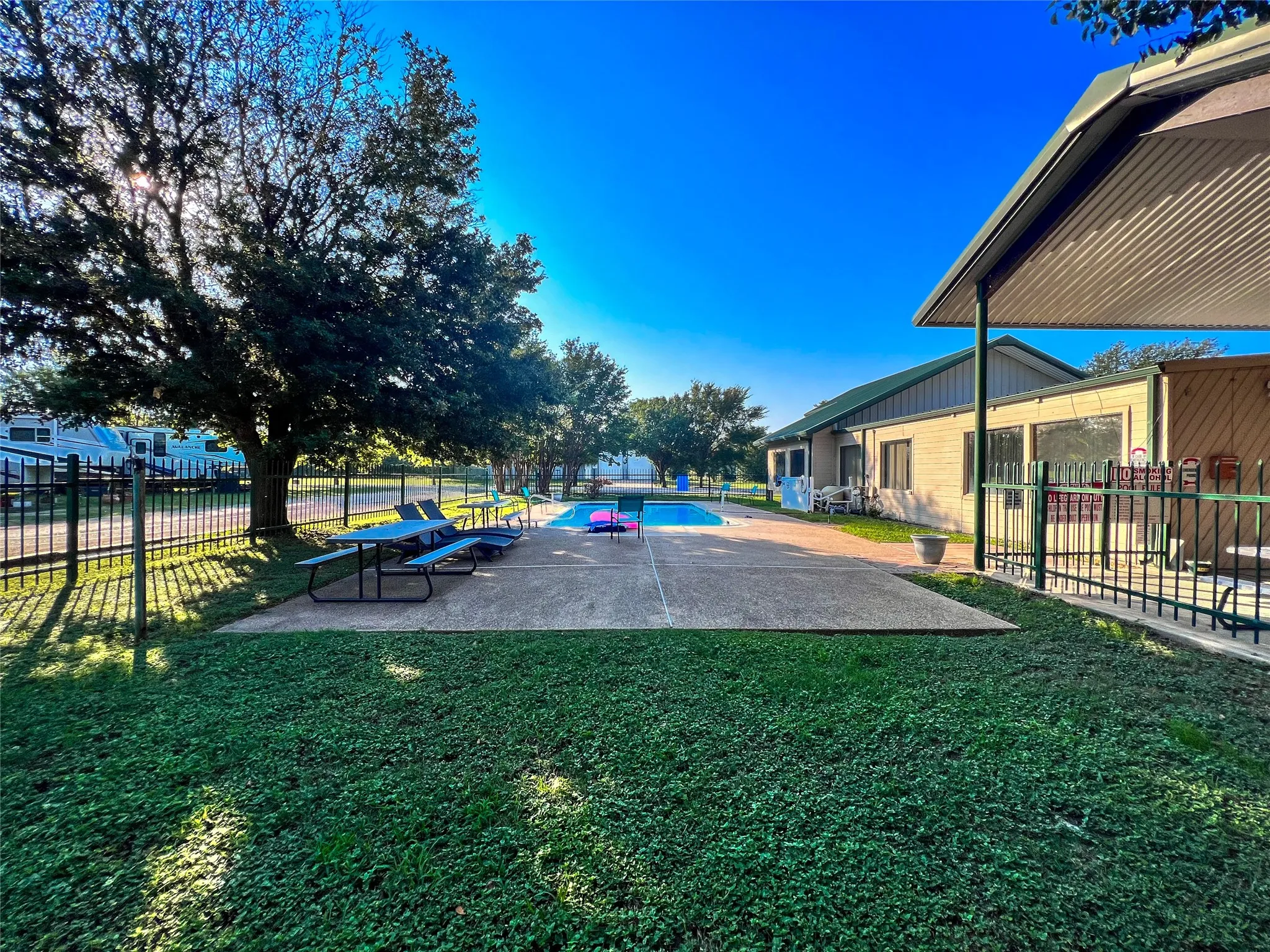Community pool area with picnic seating and shaded lawn nearby.