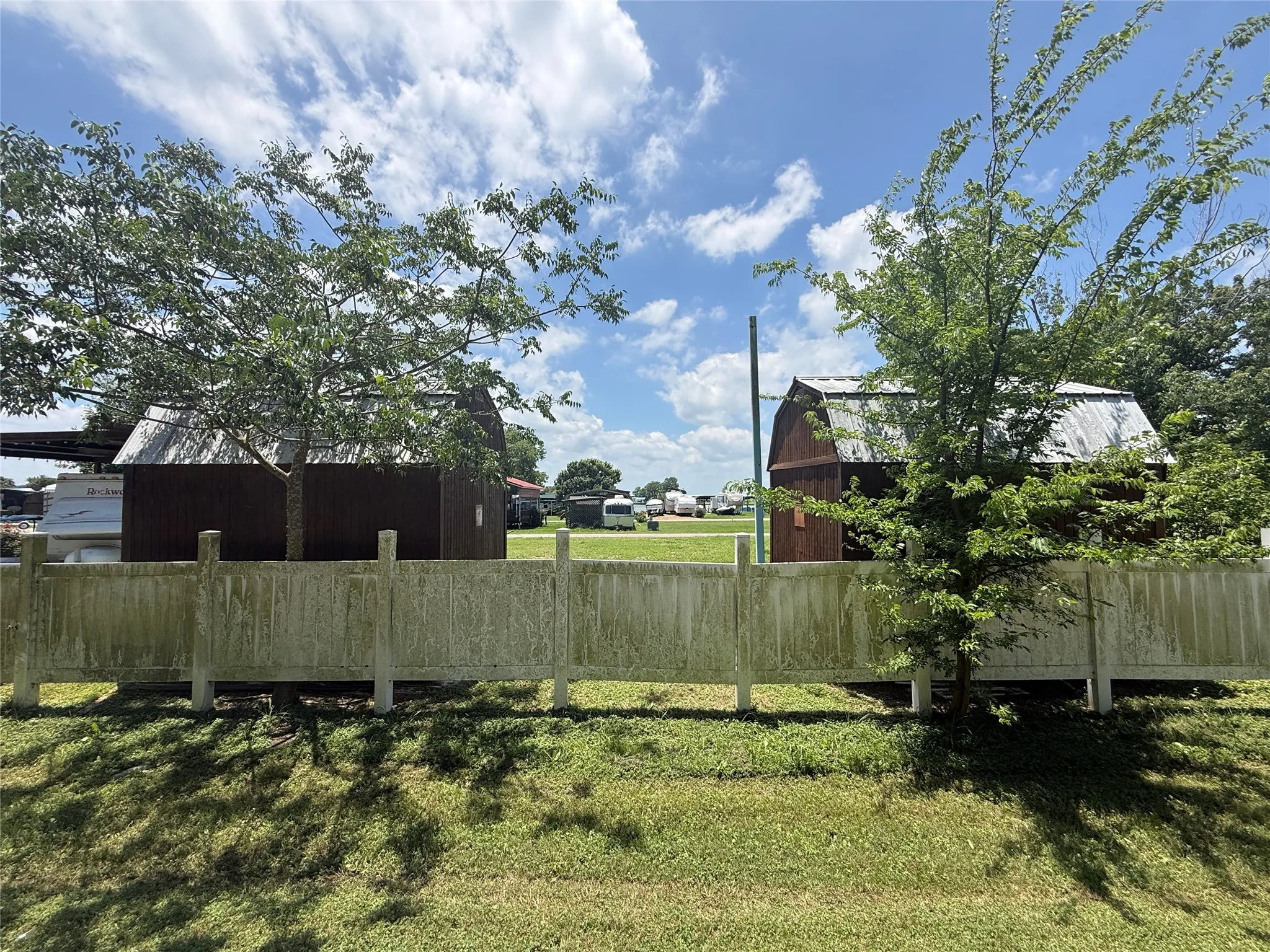 Additional fenced view highlighting the storage buildings and trees on site.