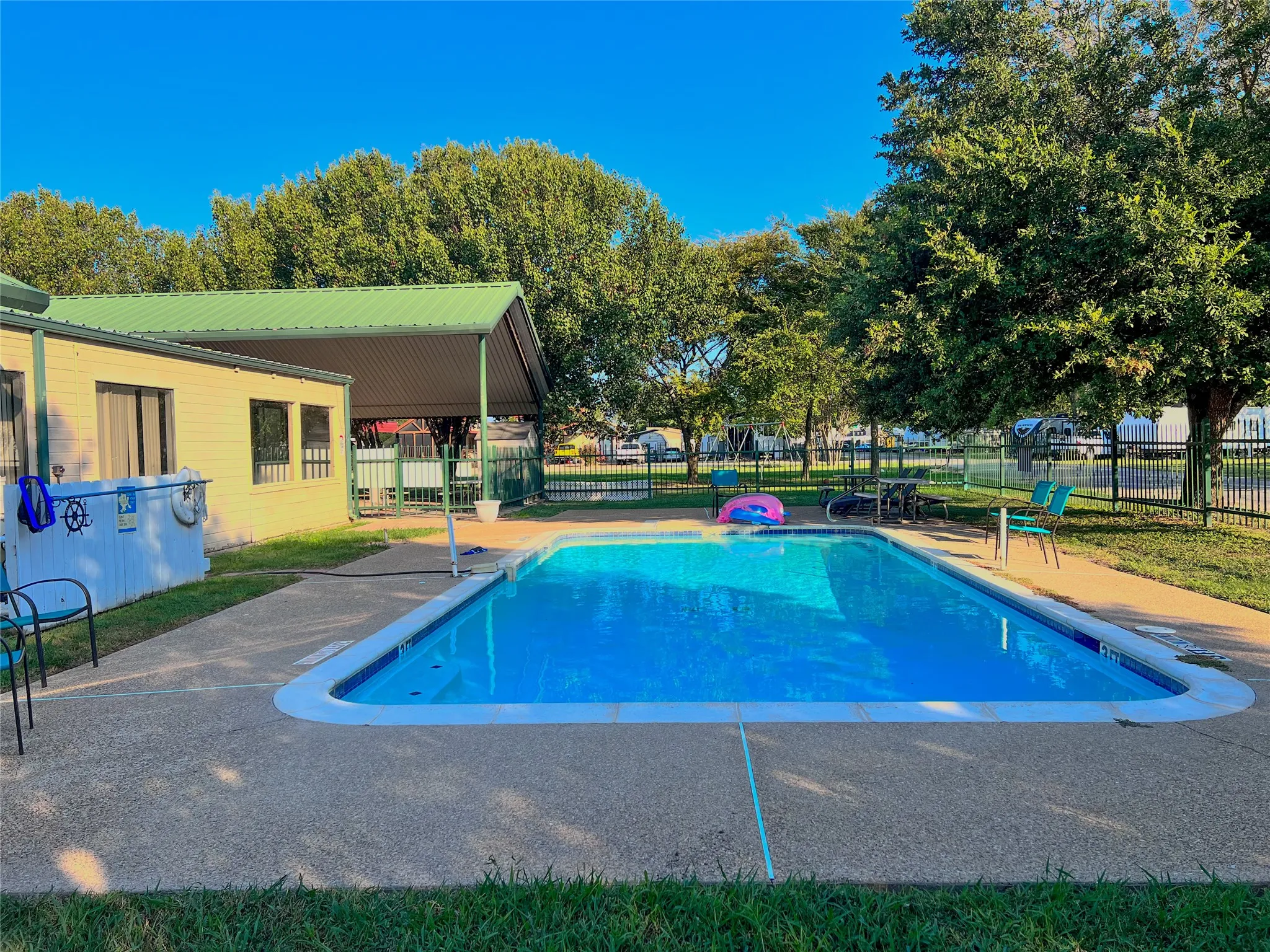 Community pool with clubhouse-style building and shaded outdoor seating.