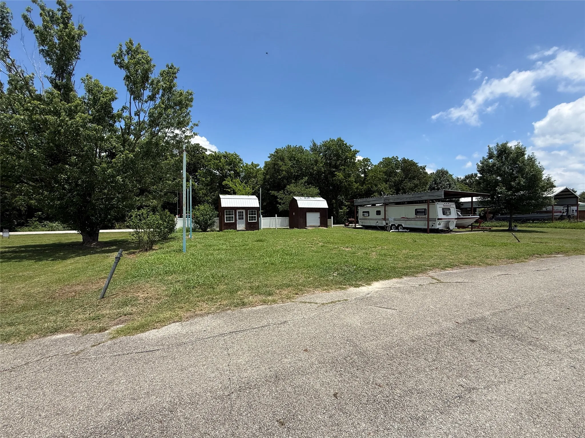 Street view of Lot 16 with open grassy space and storage buildings.