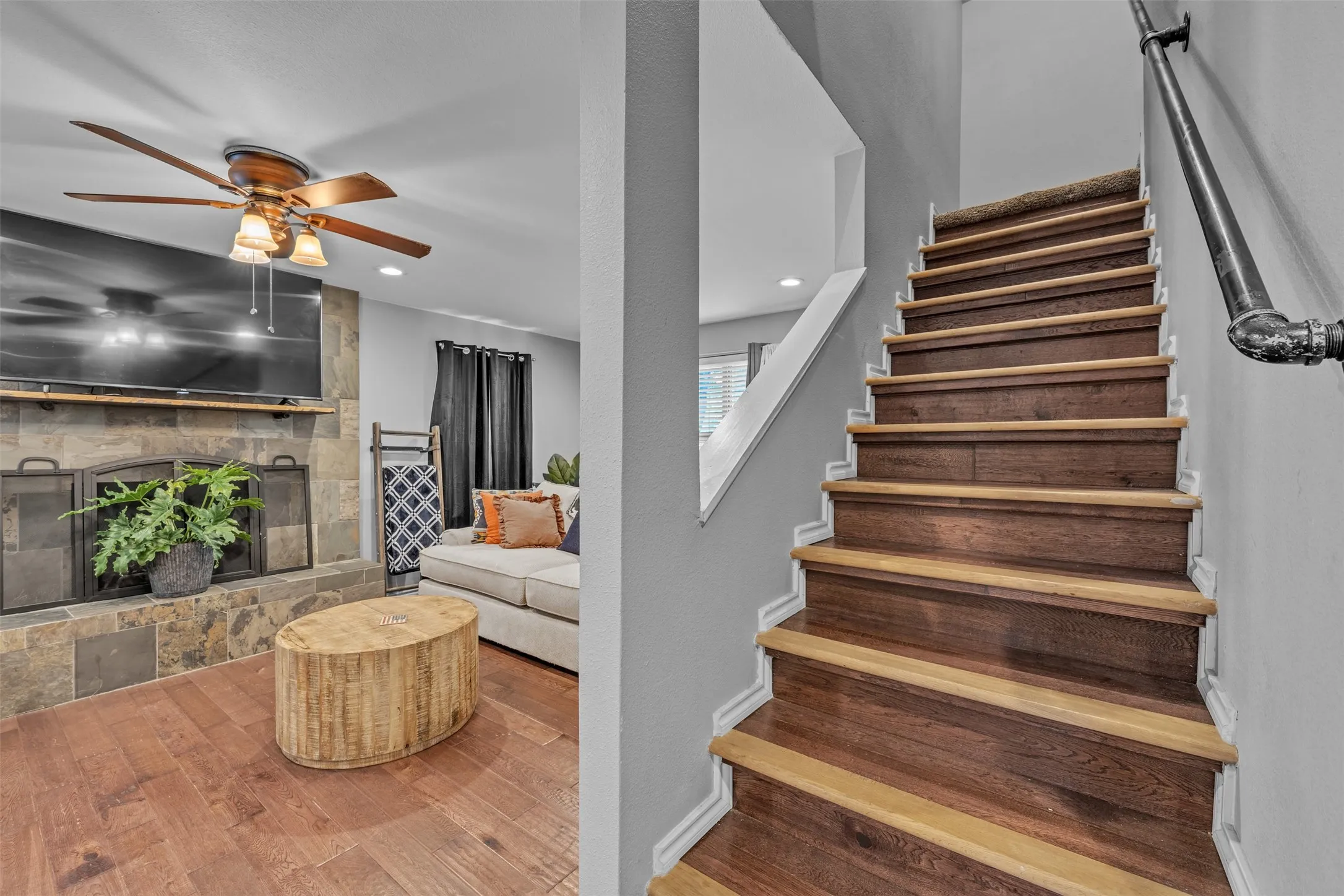 Wood-finish staircase featuring carpeted risers and a dark industrial-style handrail