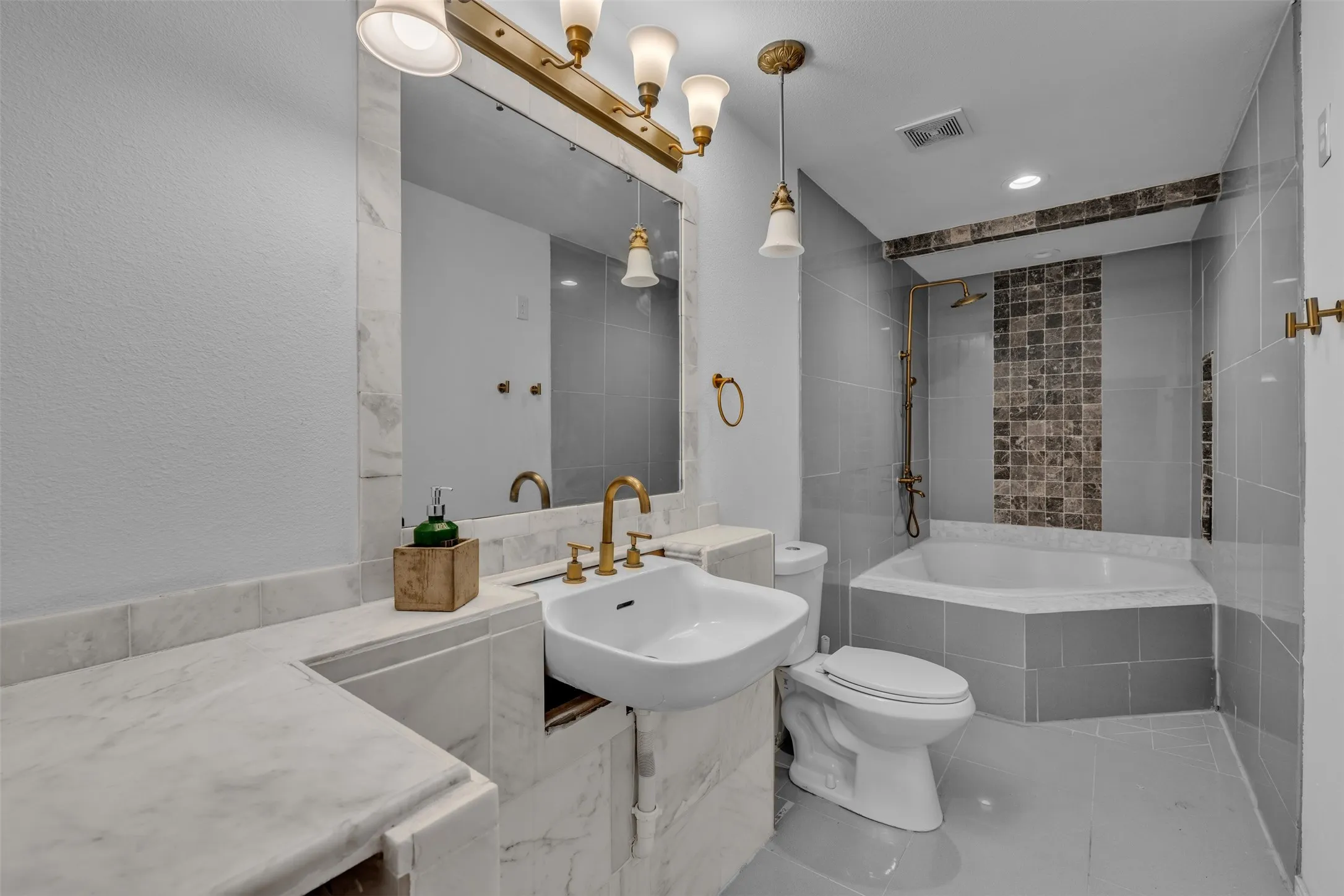 Bathroom featuring a corner soaking tub, a vessel sink, and an integrated marble vanity