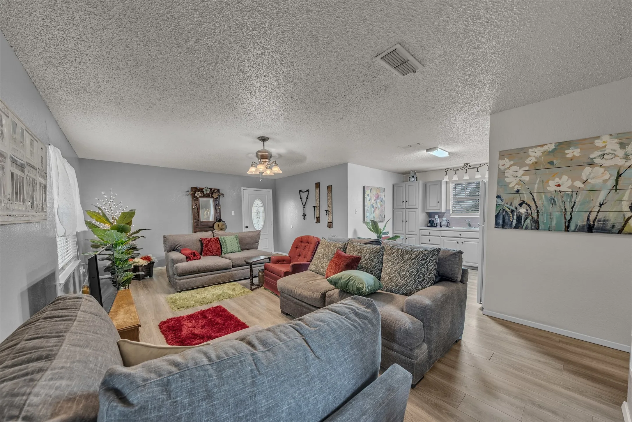 Open-concept living area with wood-finish flooring, light gray walls, and a ceiling fan in guest quarters