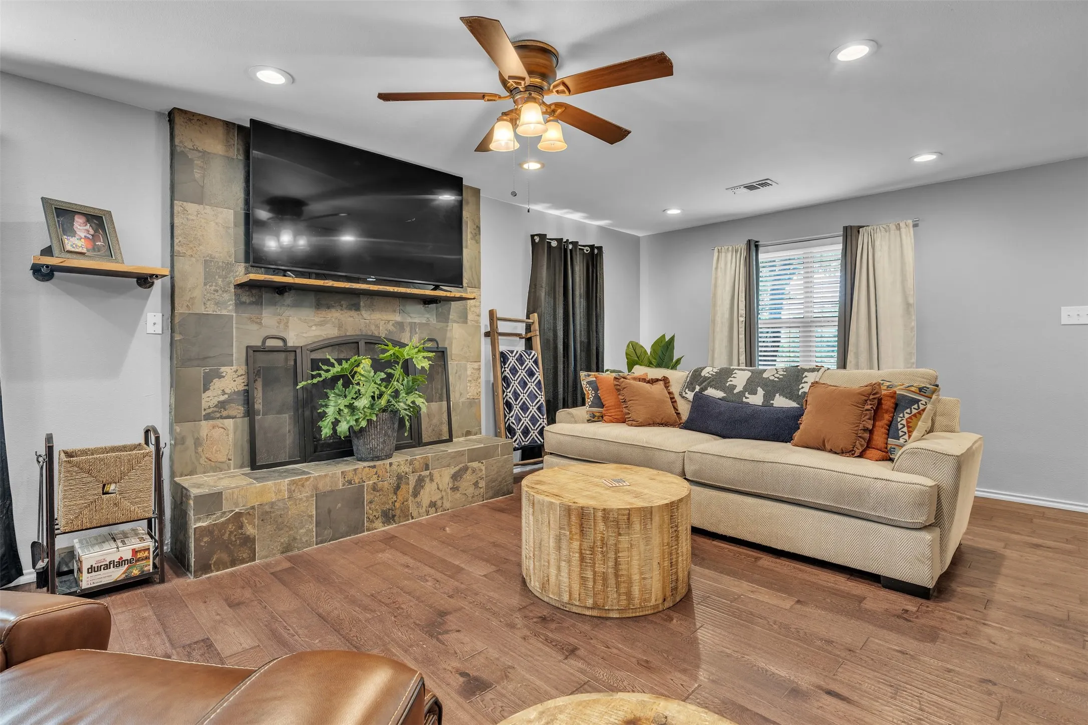 Living area featuring a stone-clad fireplace with a wood mantel, wood-finish flooring, and recessed lighting