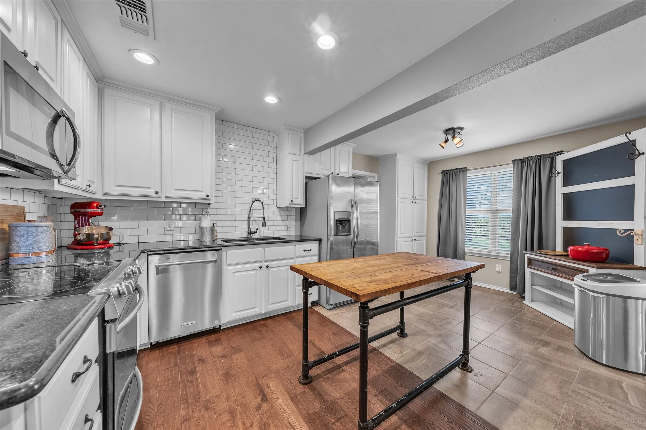 Kitchen featuring white shaker cabinetry, stainless steel appliances, dark countertops, and a white subway tile backsplash