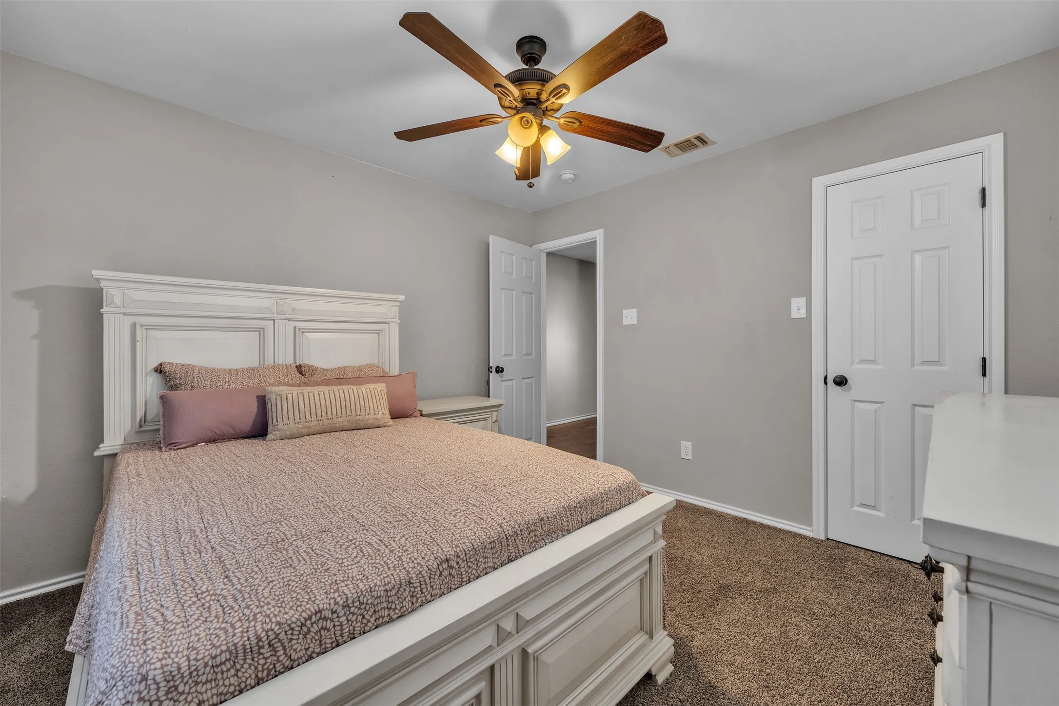 Interior room featuring light gray wall paint, brown carpet flooring, a ceiling fan with light fixture, and white paneled doors