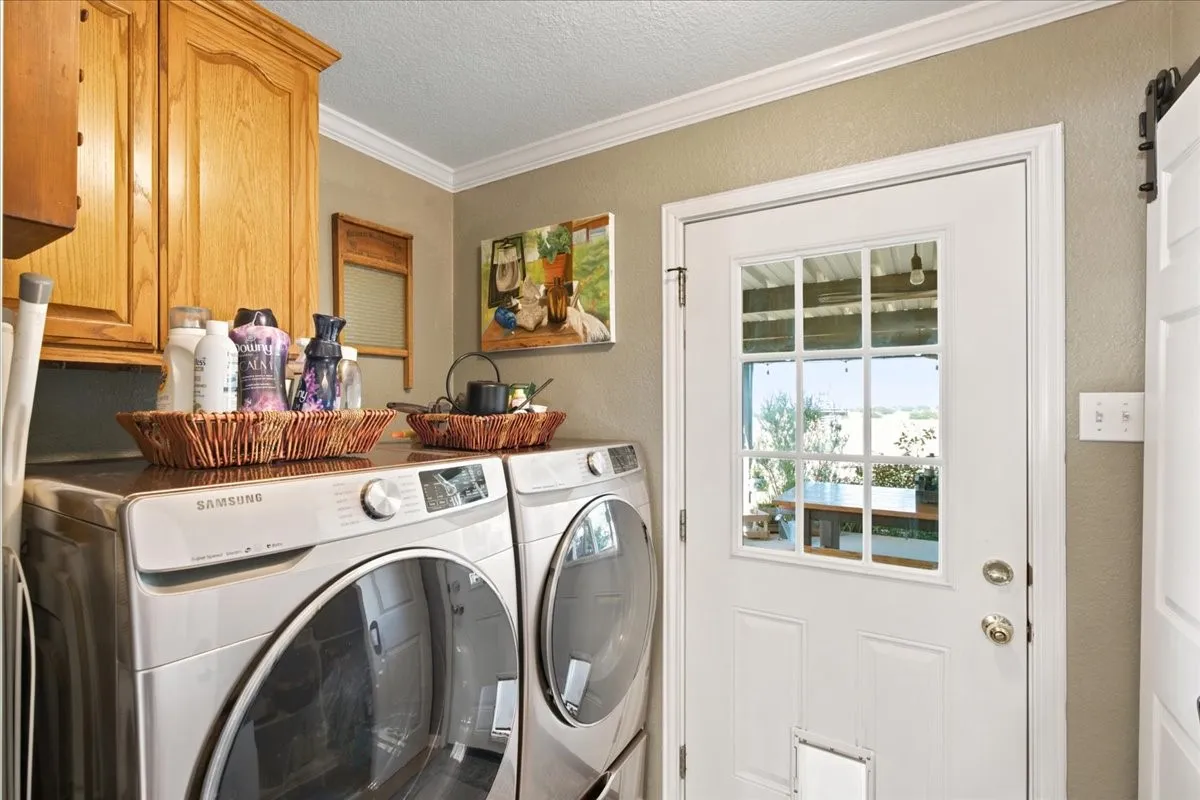 Utility area featuring overhead wood cabinetry, crown molding, and a white paneled door with a multi-pane glass insert