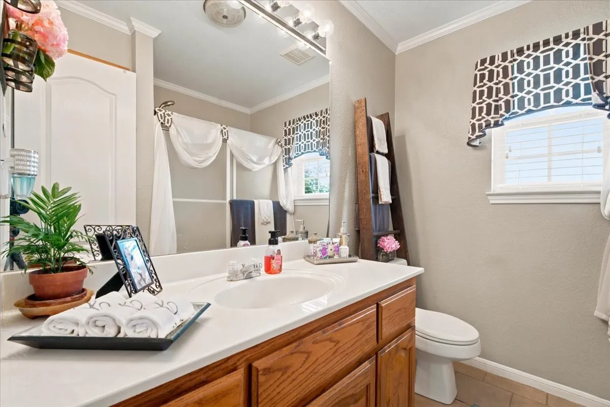 Bathroom featuring a vanity with a white countertop and wood-finish cabinetry, a single sink, and a large mirror