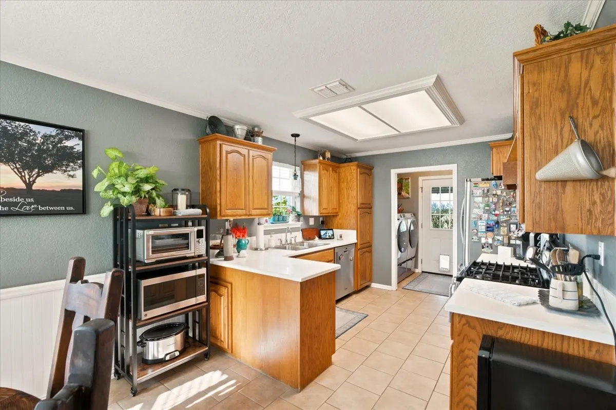 Kitchen featuring wood cabinetry, white countertops, stainless steel appliances, and tile flooring