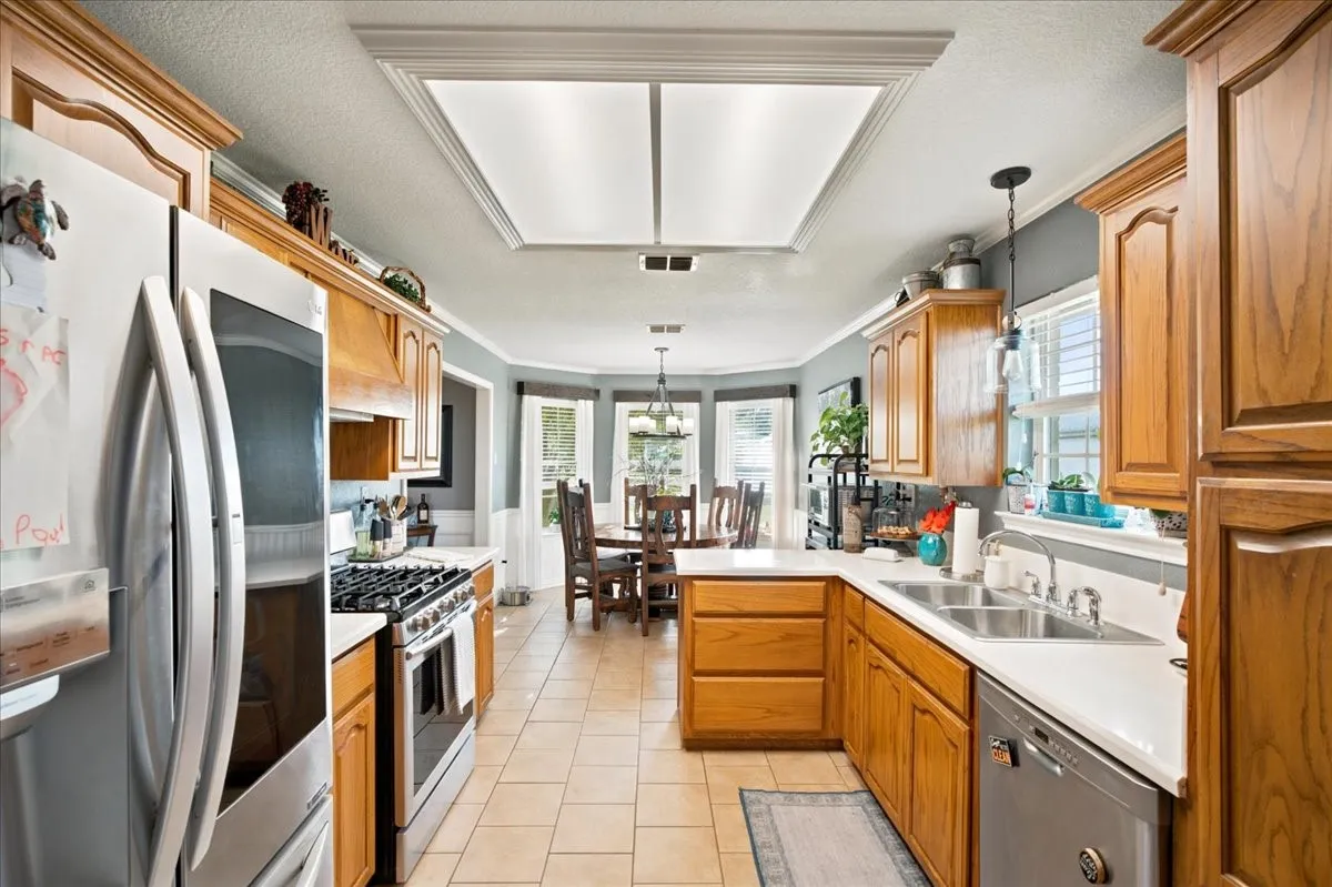 Kitchen featuring wood cabinetry, stainless steel appliances, light-toned countertops, and tile flooring
