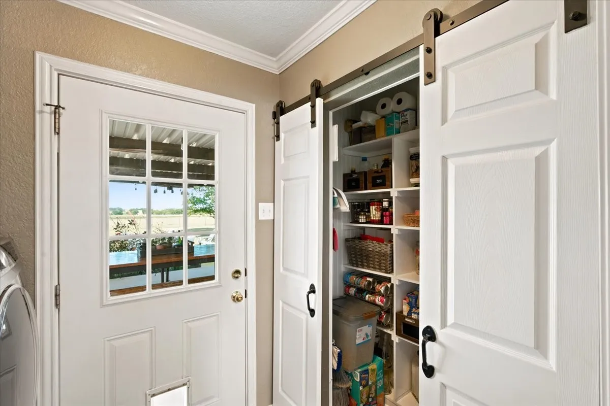 Built-in storage solutions featuring barn-style sliding doors, paneled doors, crown molding, and a transom door window