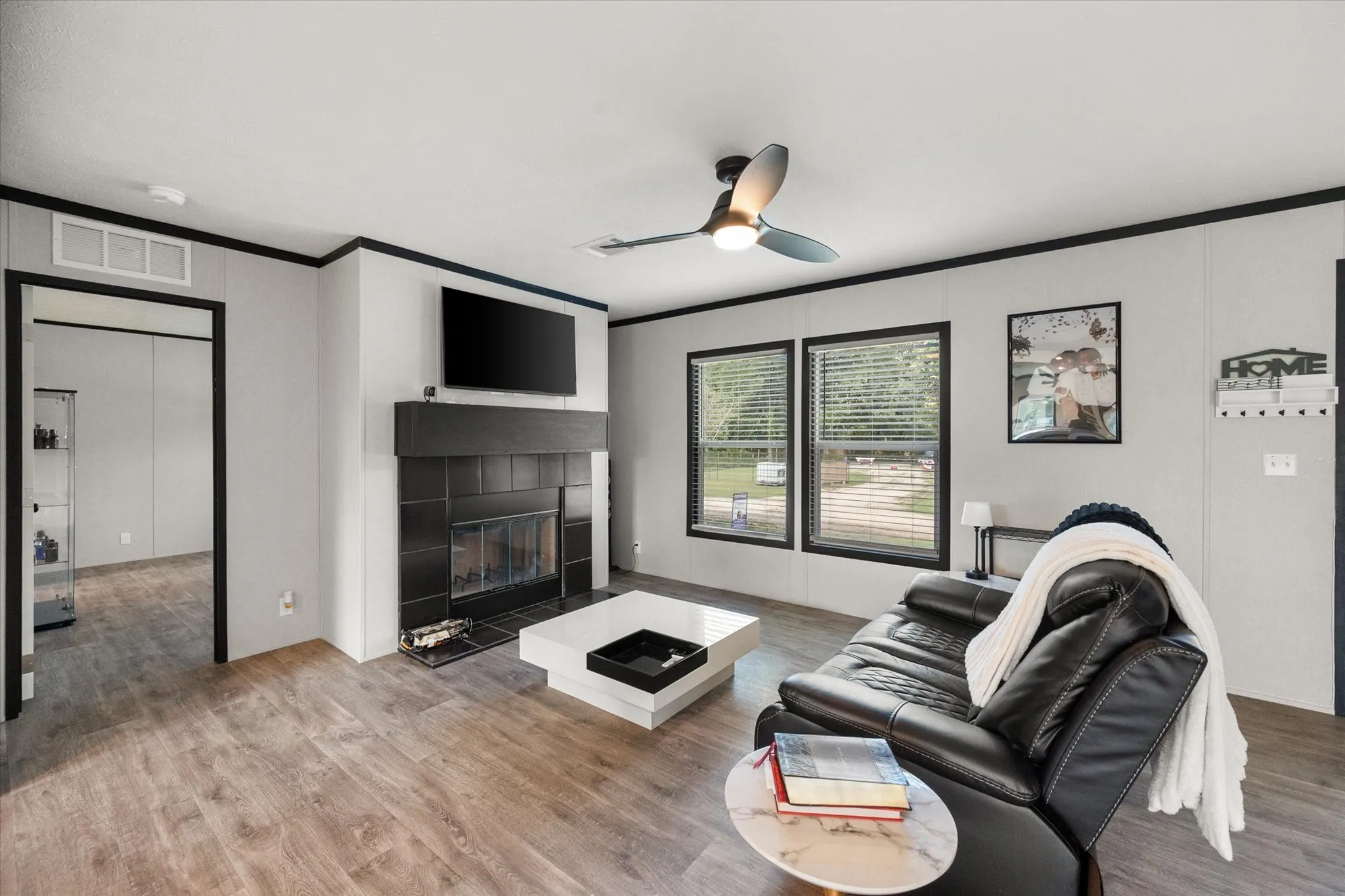 Living area featuring a contemporary ceiling fan, and a fireplace with a black tile surround and mantle
