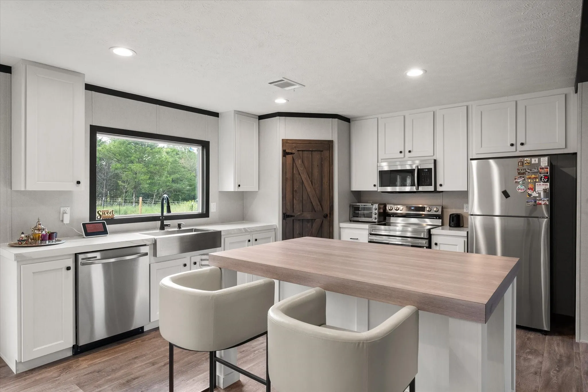 Modern kitchen featuring white shaker cabinetry, stainless steel appliances, a wood-finish island countertop, and wood-finish flooring