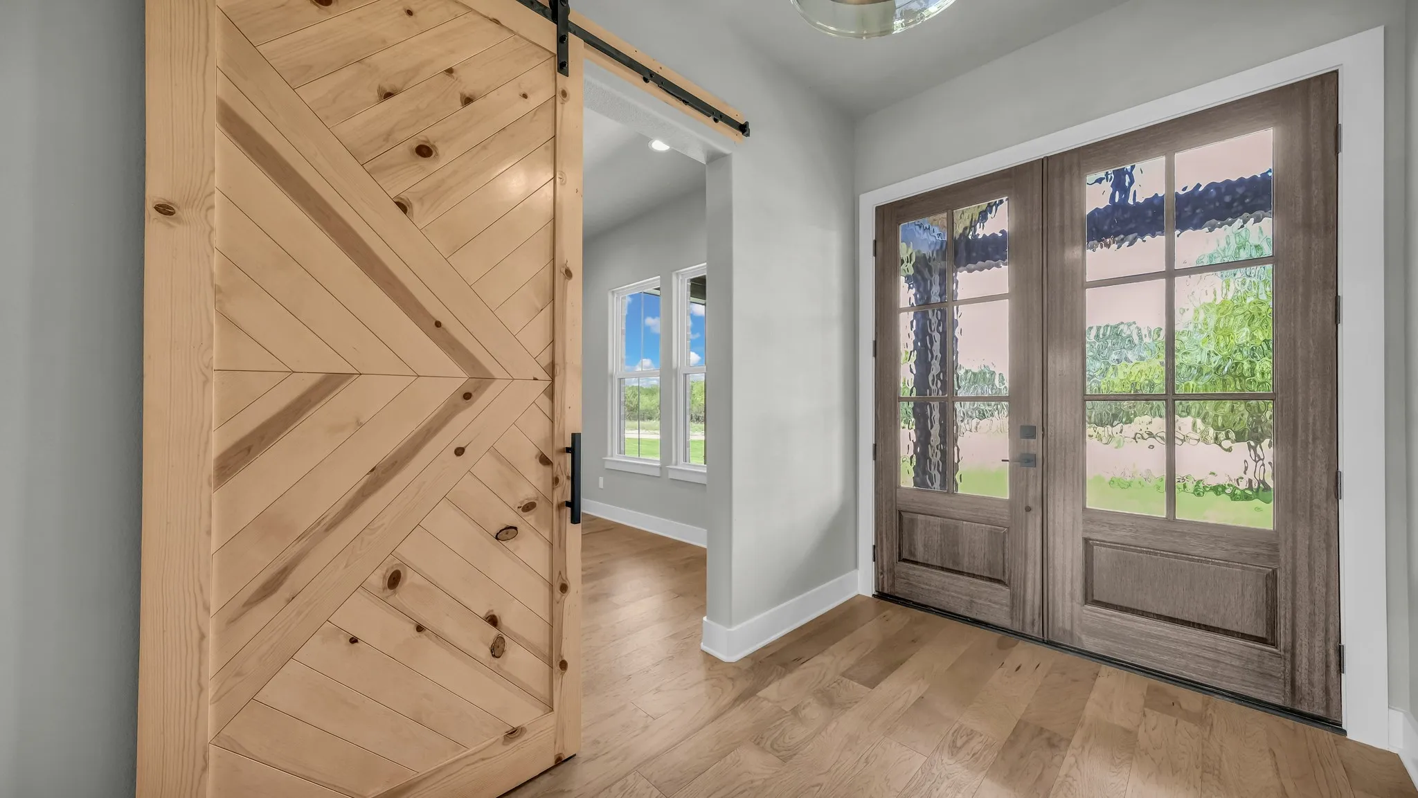 Double entry doors with decorative glass panels and wood-finish flooring