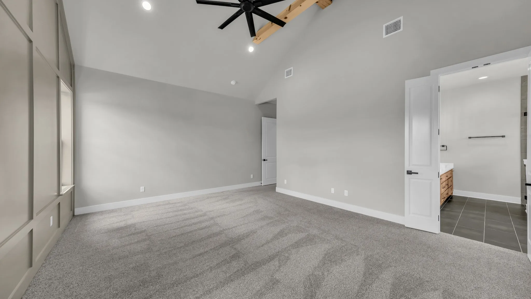 Spacious room with vaulted ceilings and exposed wood beam accents