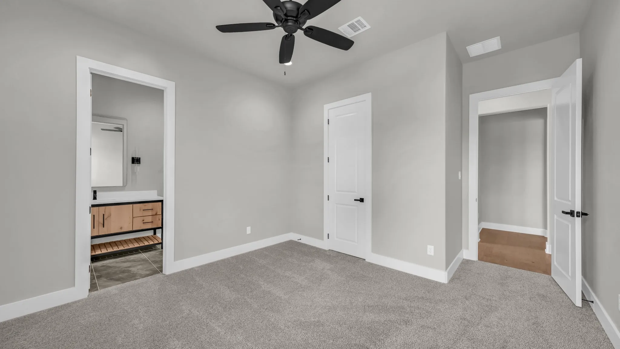 Carpeted room with a black ceiling fan, light gray walls, and white trim