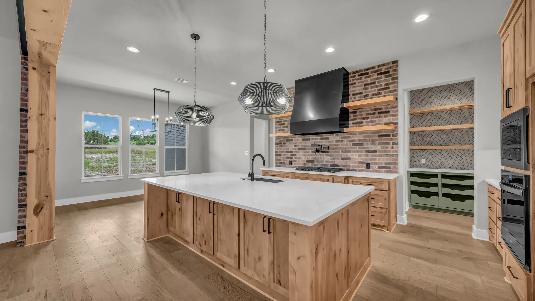 Kitchen featuring a large island with white countertop, wood-finish cabinetry, and industrial-style pendant lighting