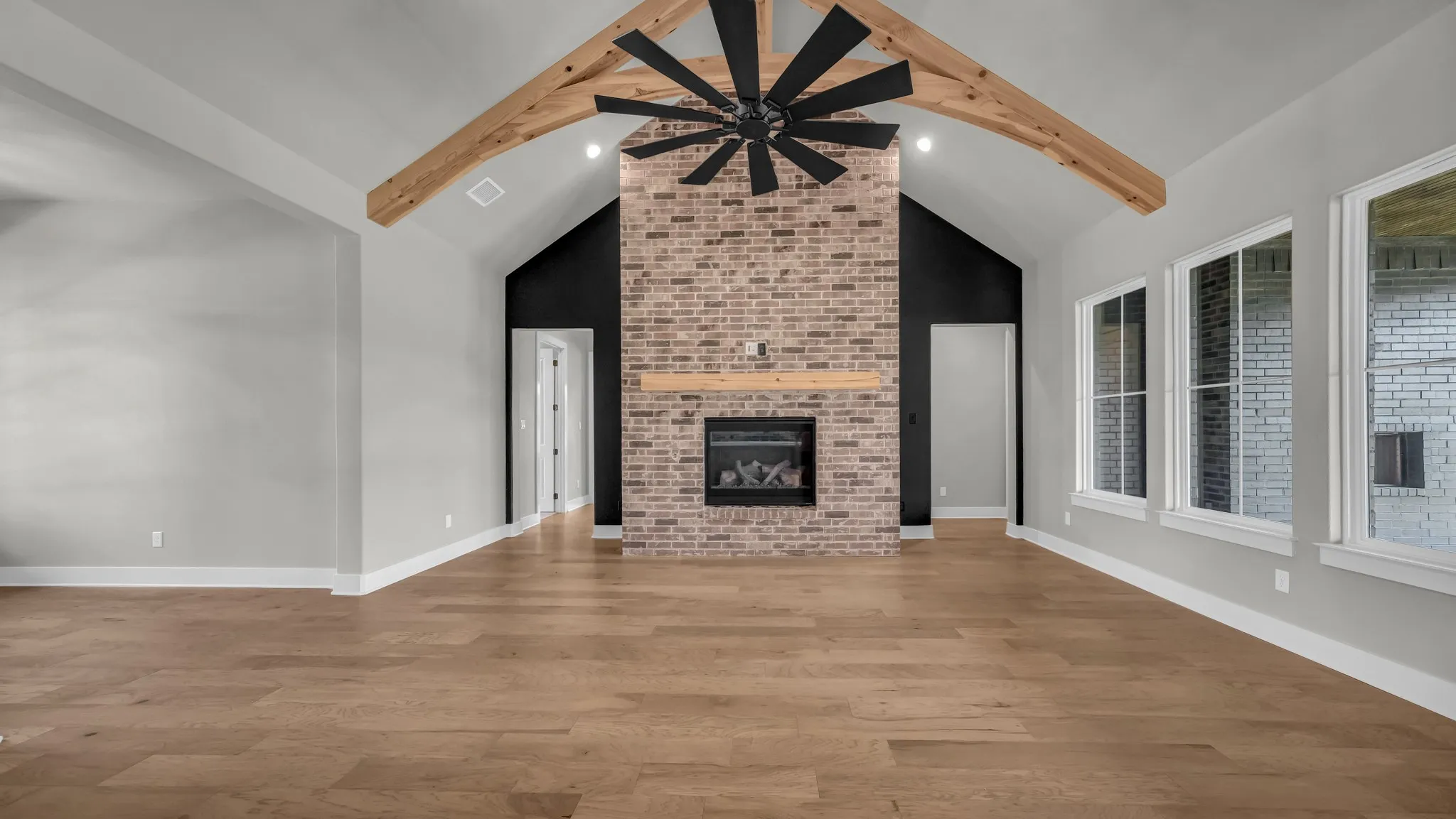 Vaulted ceiling with exposed wood beams and a large ceiling fan