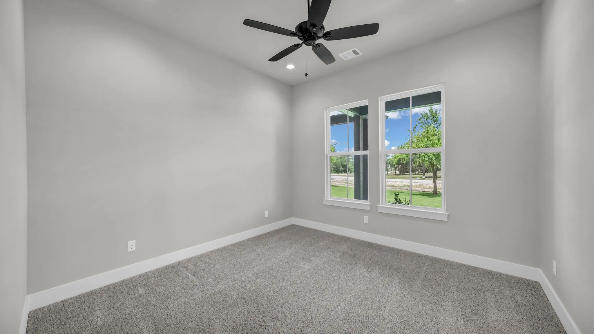 Carpeted room with a vaulted ceiling and two white-framed windows