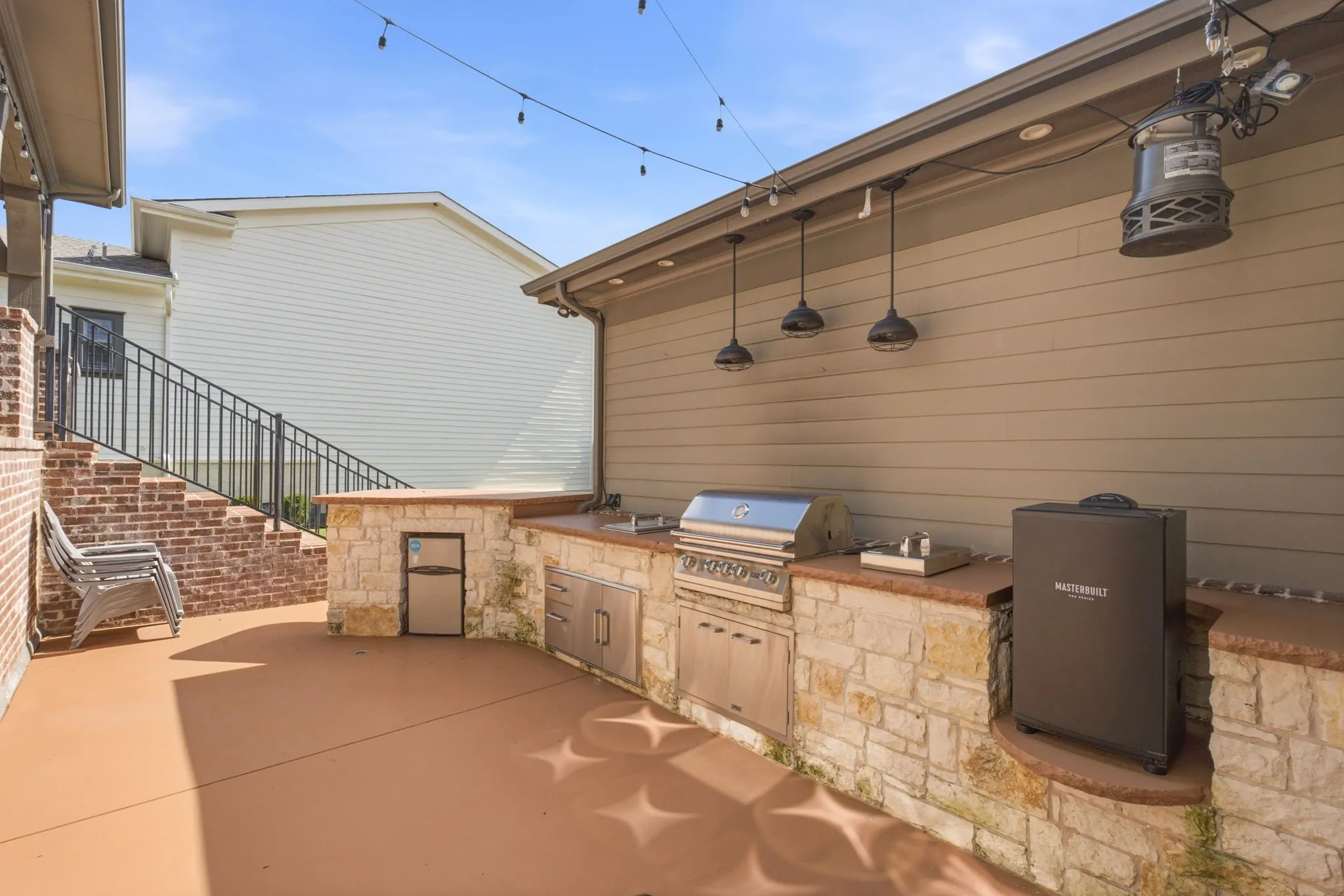 This beautifully designed outdoor patio features a premium built-in grill and an integrated refrigerator, creating an ideal setting for seamless al fresco dining and entertaining. The space also includes a dedicated, reinforced area specifically customized to accommodate a smoker or Big Green Egg, making it a perfect retreat for culinary enthusiasts who enjoy outdoor cooking.