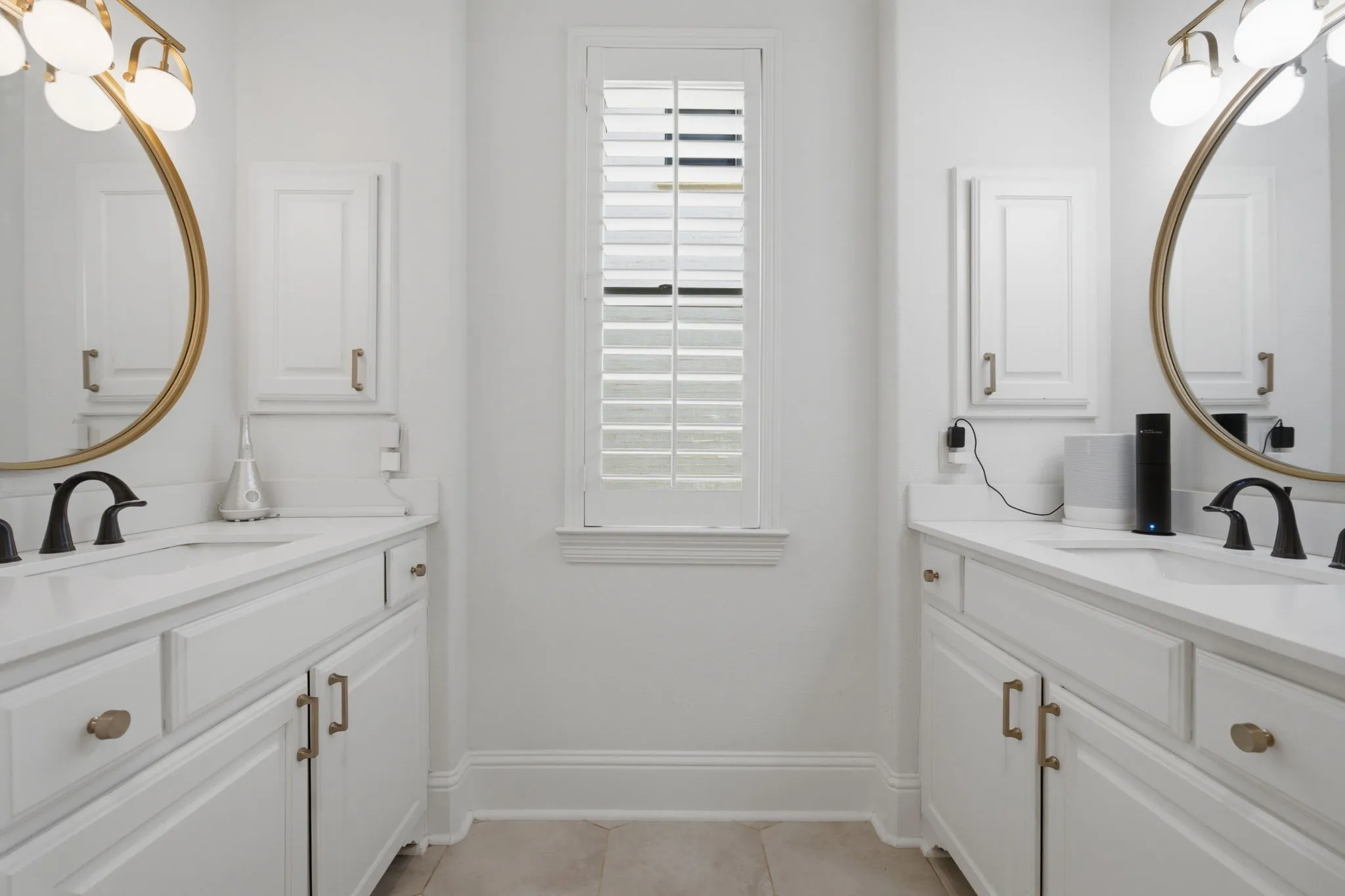 This spacious primary bathroom features elegant his and hers dual vanities, each equipped with dedicated, individual medicine cabinets for optimal organization. The room is beautifully illuminated by a accent window that provides natural light, creating a bright and inviting atmosphere.