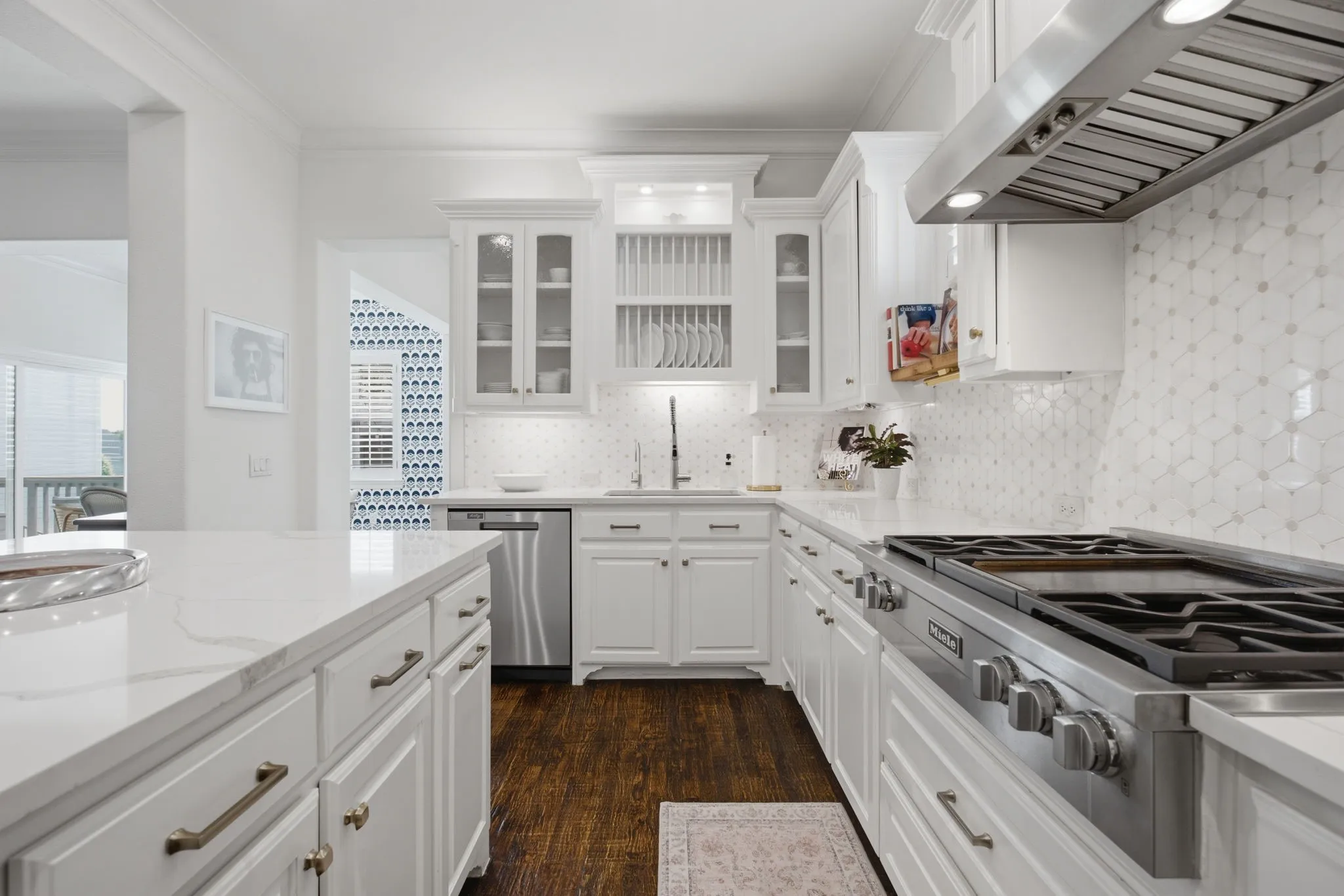 This gourmet kitchen is elegantly designed, featuring custom glass-front cabinetry, a professional-grade gas cooktop complete with an integrated grill, and a charming plate rack conveniently positioned above the farmhouse-style sink.